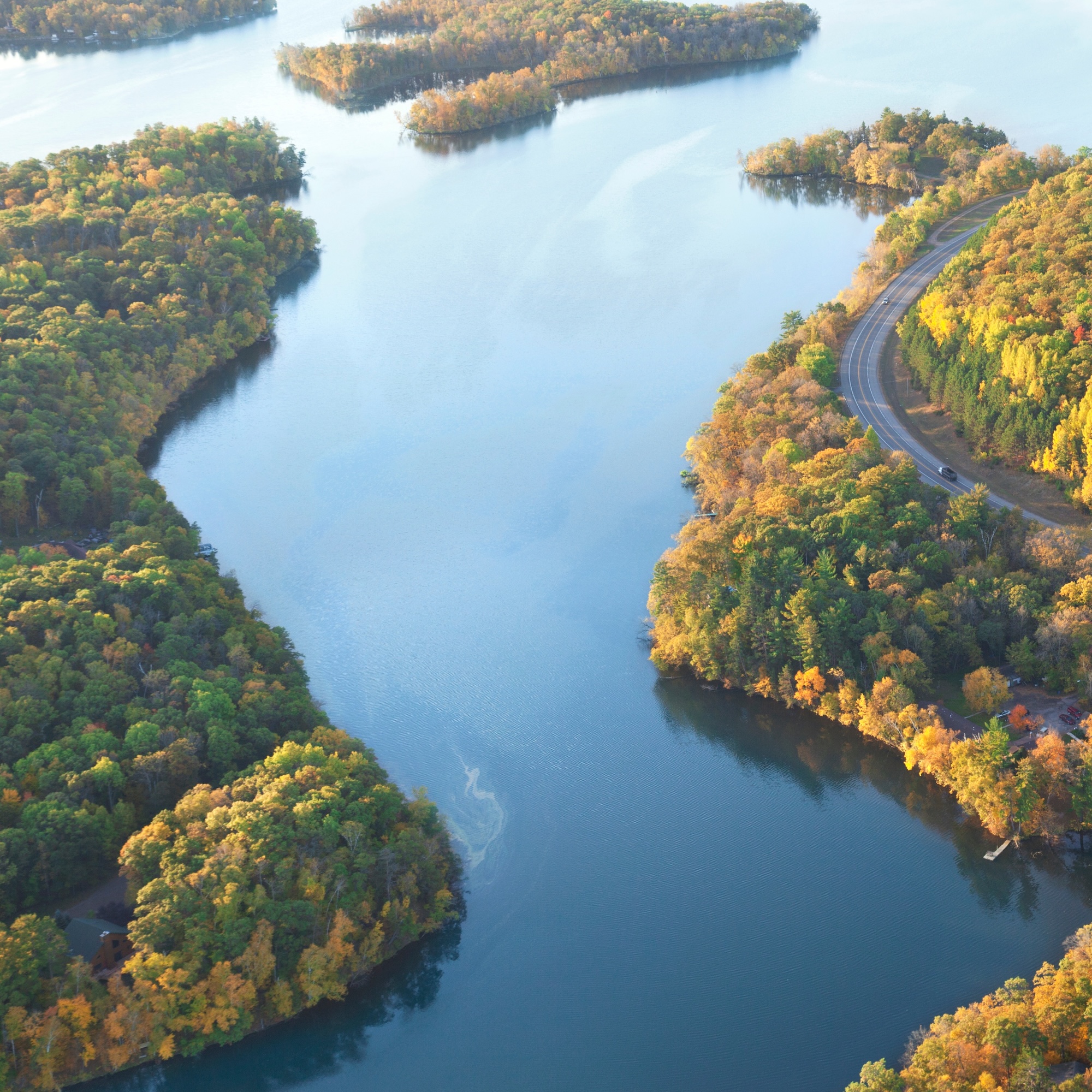 Aerial view of a winding river with islands and autumn foliage.