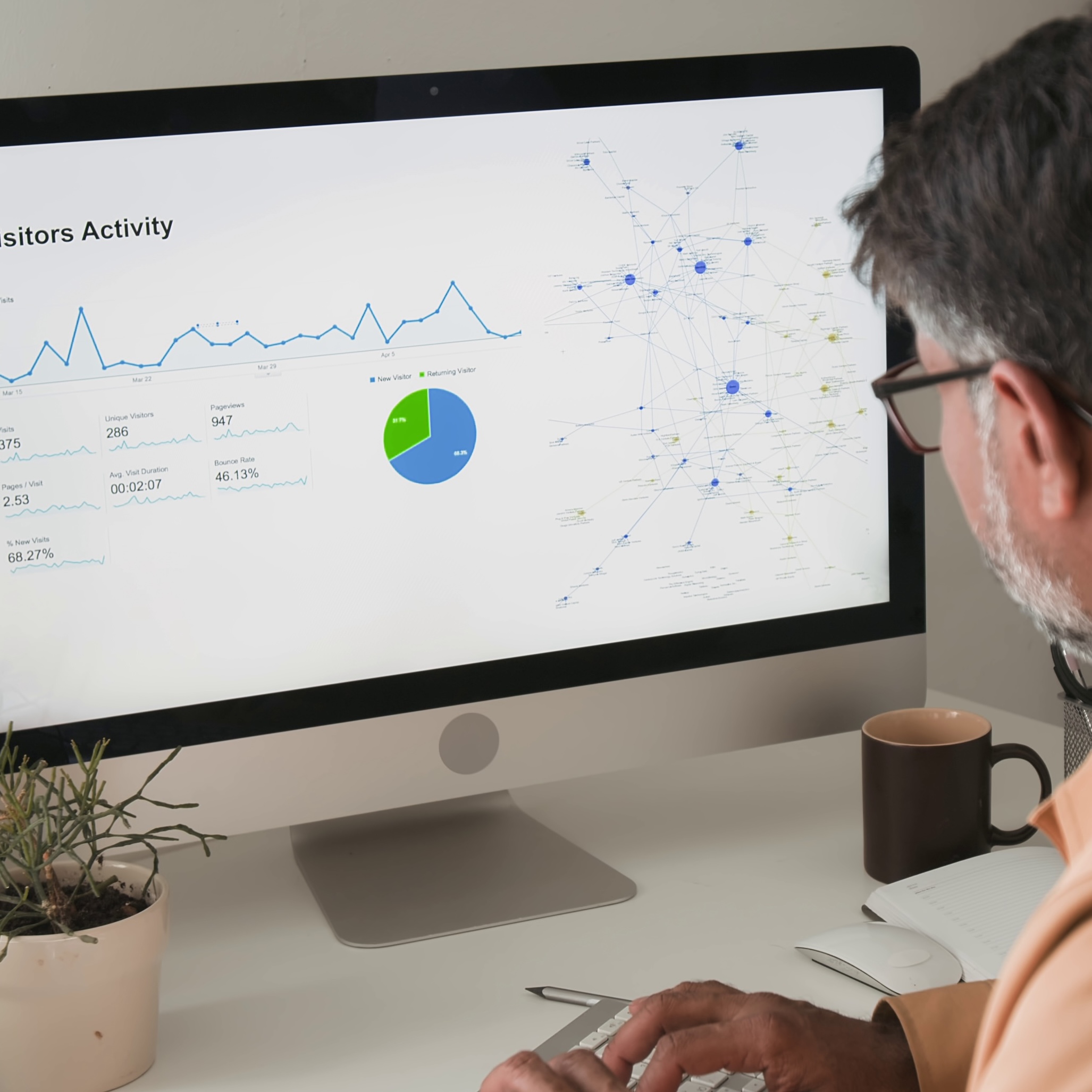 Man looks at computer screen with analytics data and network diagram.