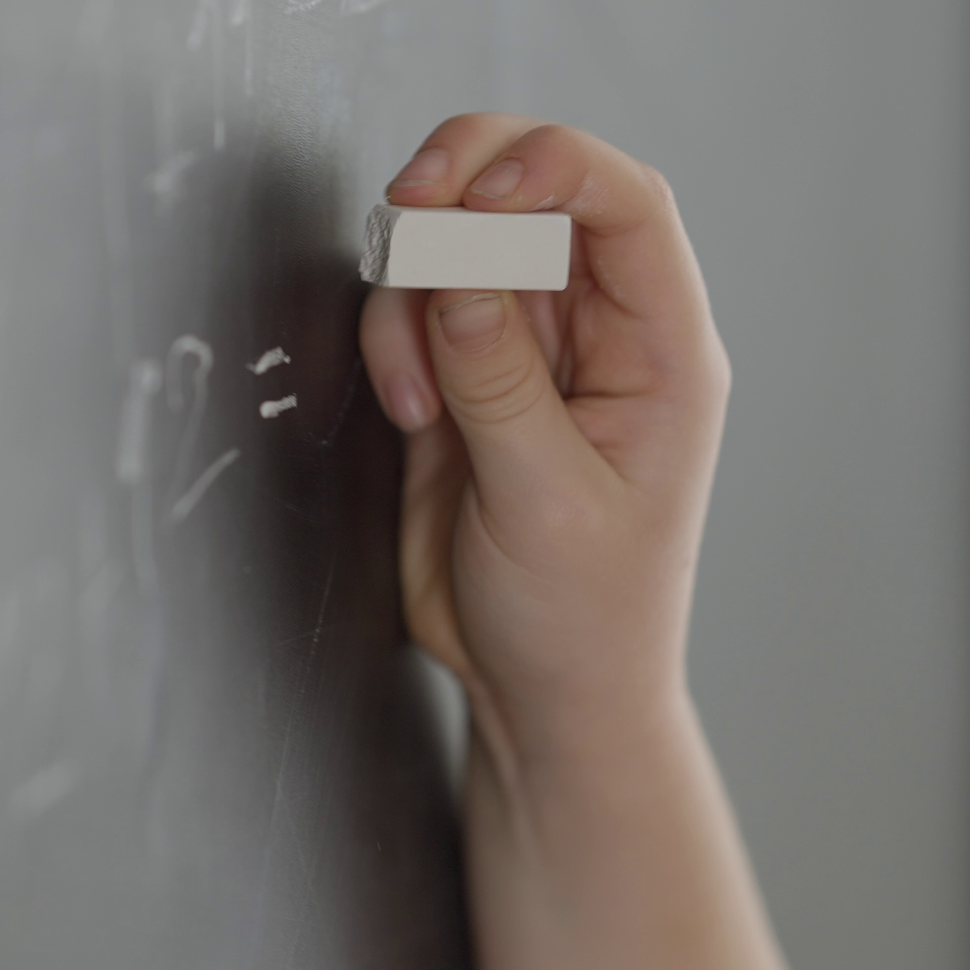 Hand erasing chalk marks from a blackboard.