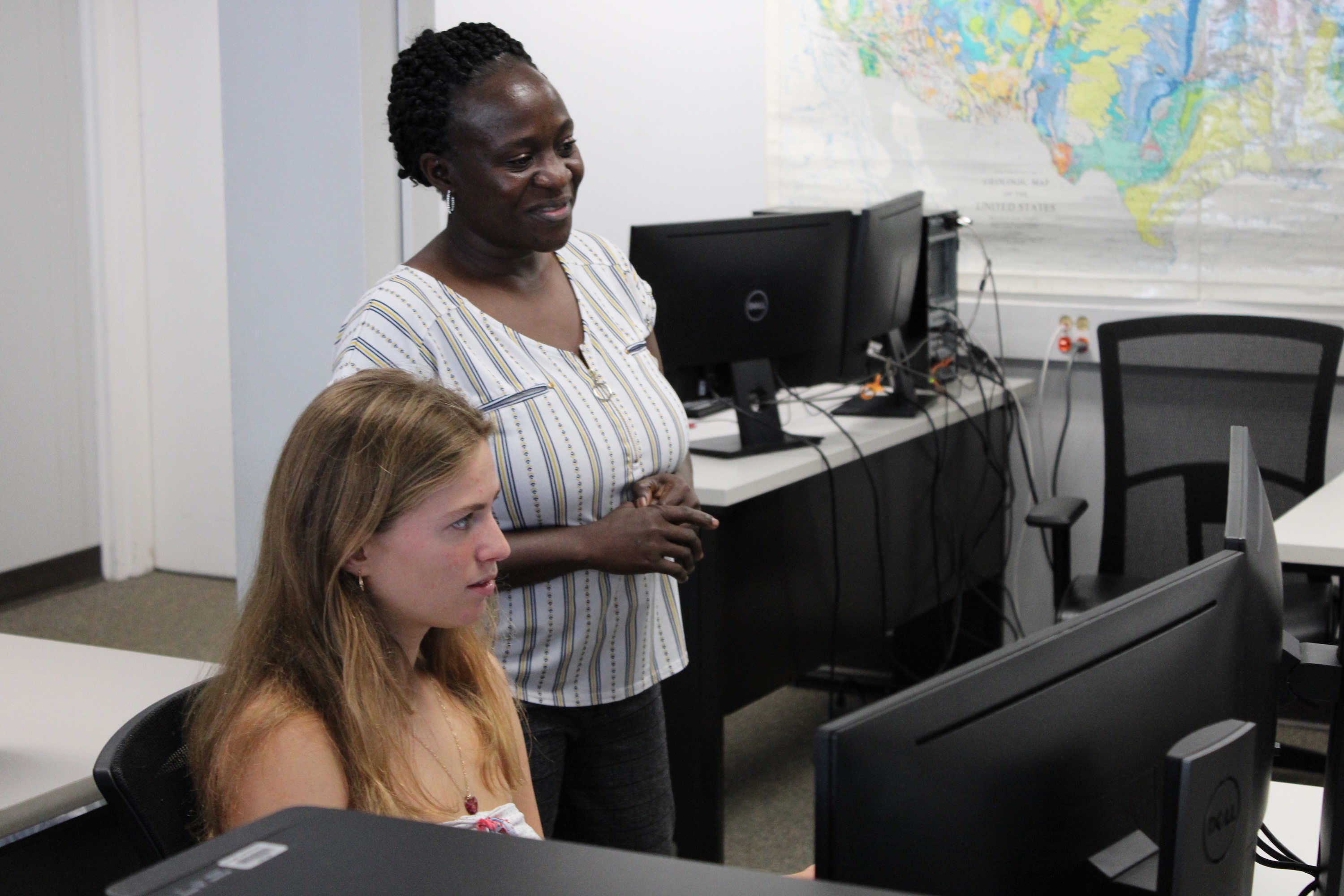 Two women, one Black and one white, work together at computers.