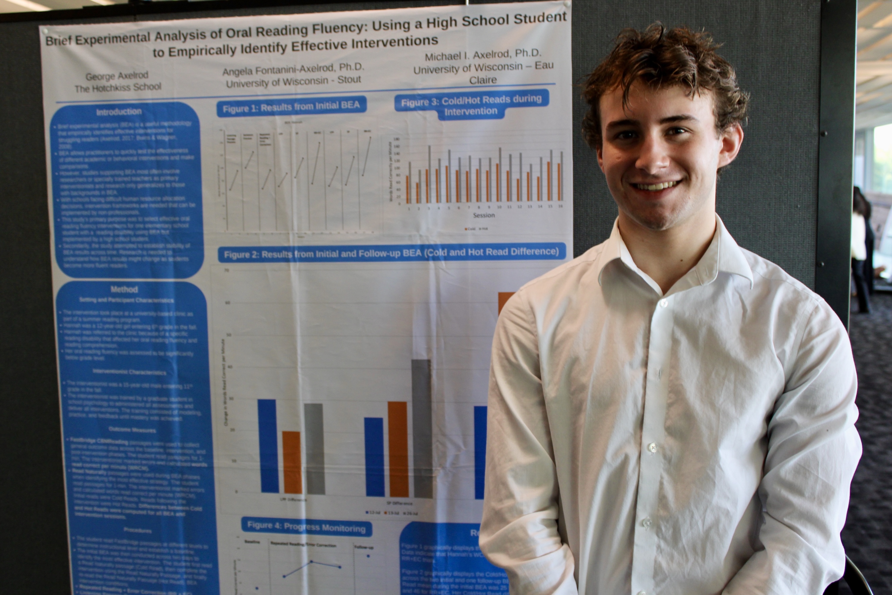 Young man in white shirt stands next to a science fair poster.