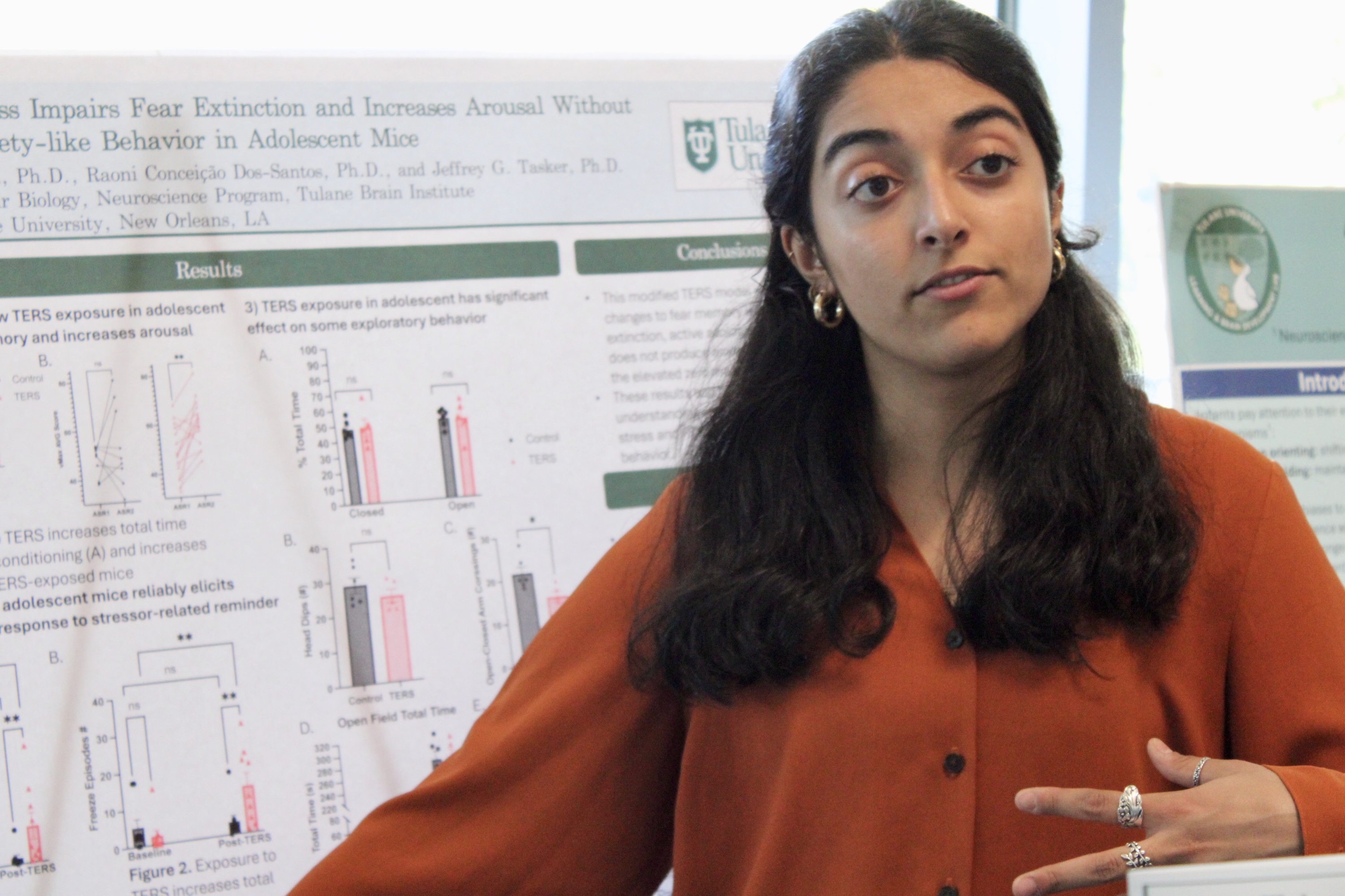 A young woman presents research at a poster session.