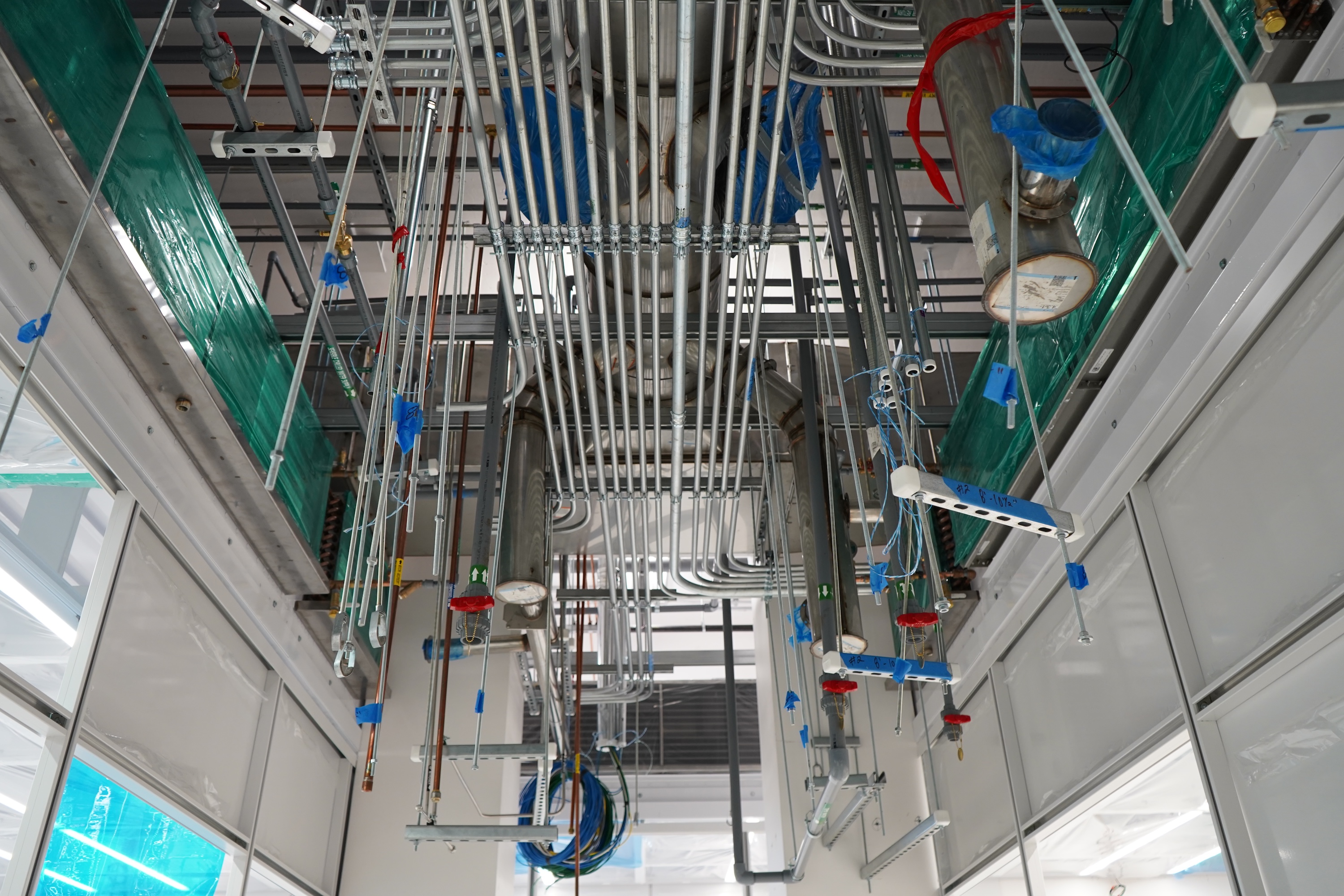 Overhead view of numerous pipes and conduits in a building under construction.