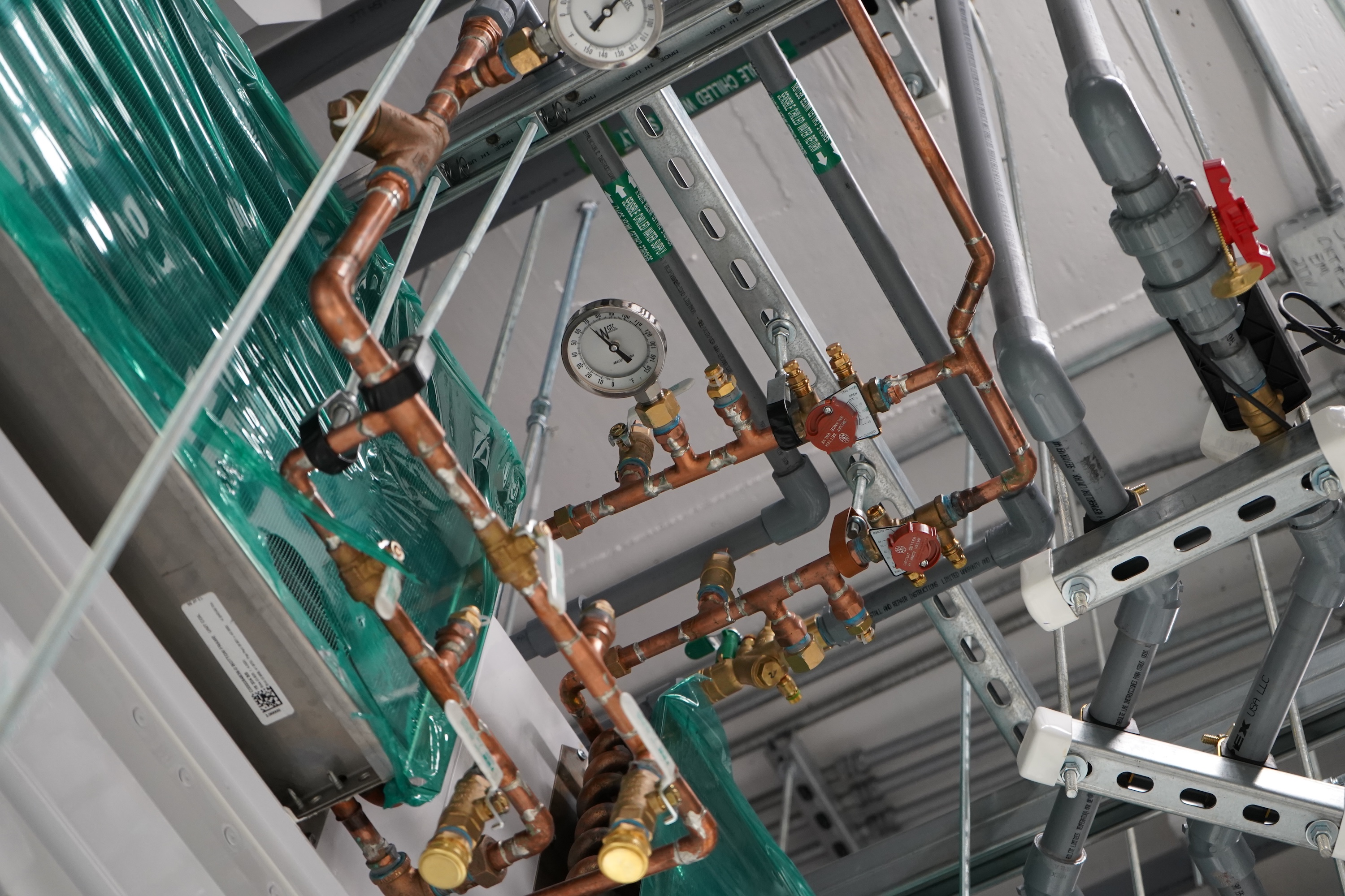 Complex network of copper pipes, valves, and gauges in an industrial setting.