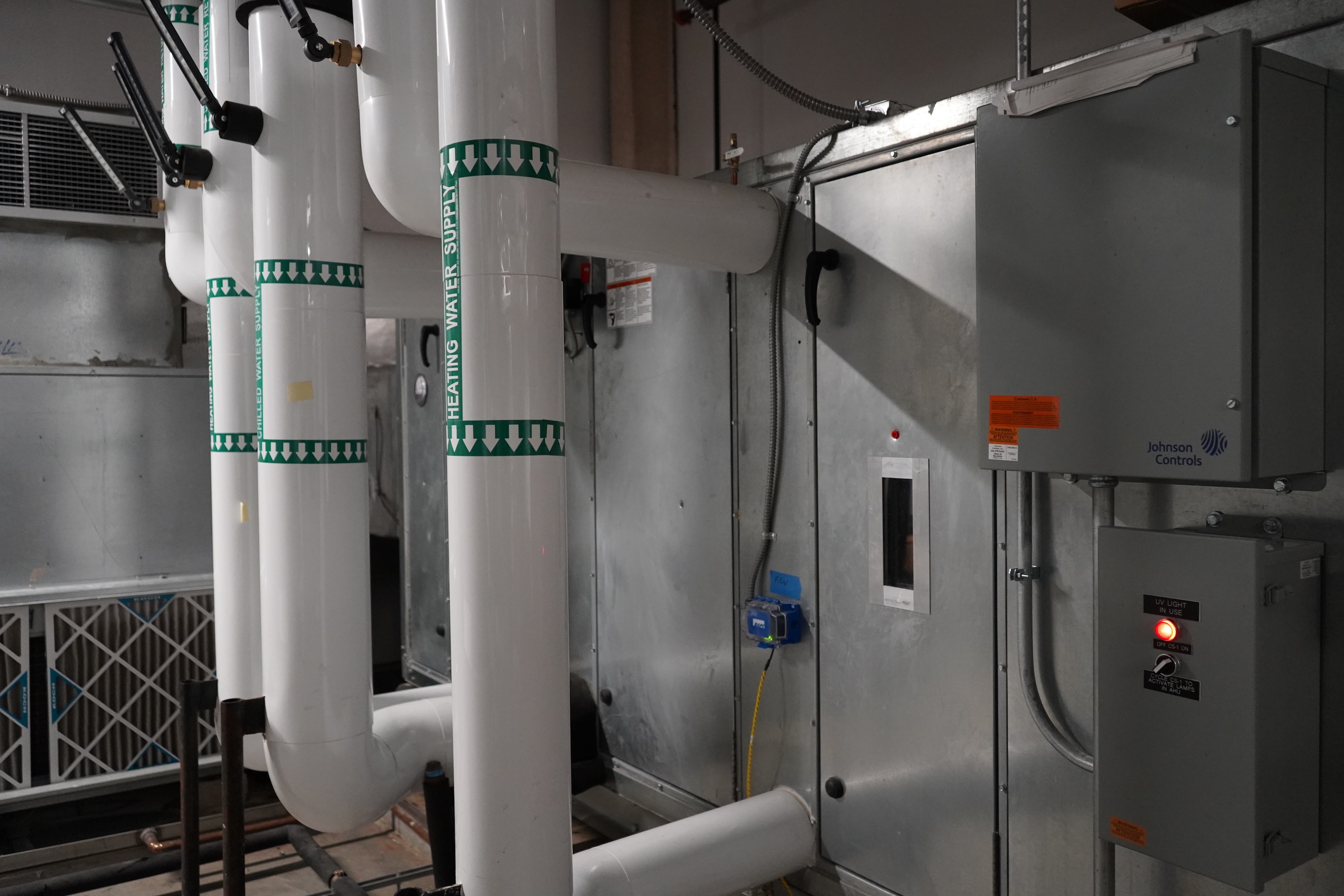 HVAC unit with large white pipes and electrical boxes.