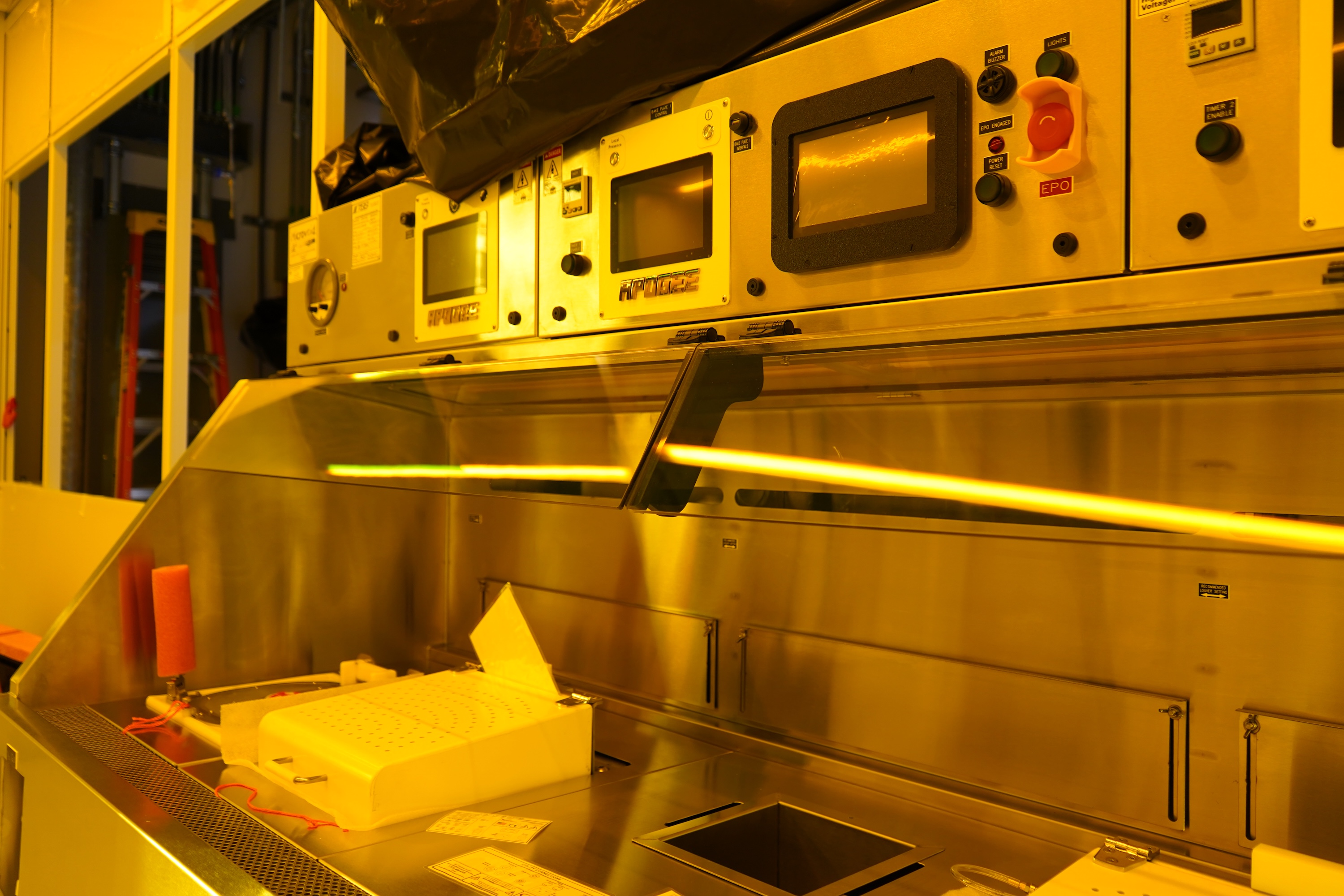Close-up of a cleanroom machine with a long rod being processed.