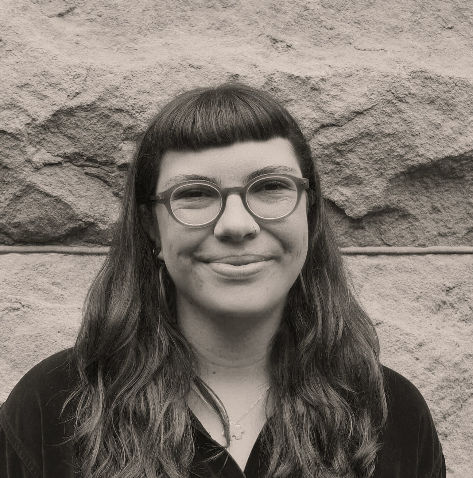 Portrait of a woman with glasses and bangs, smiling.
