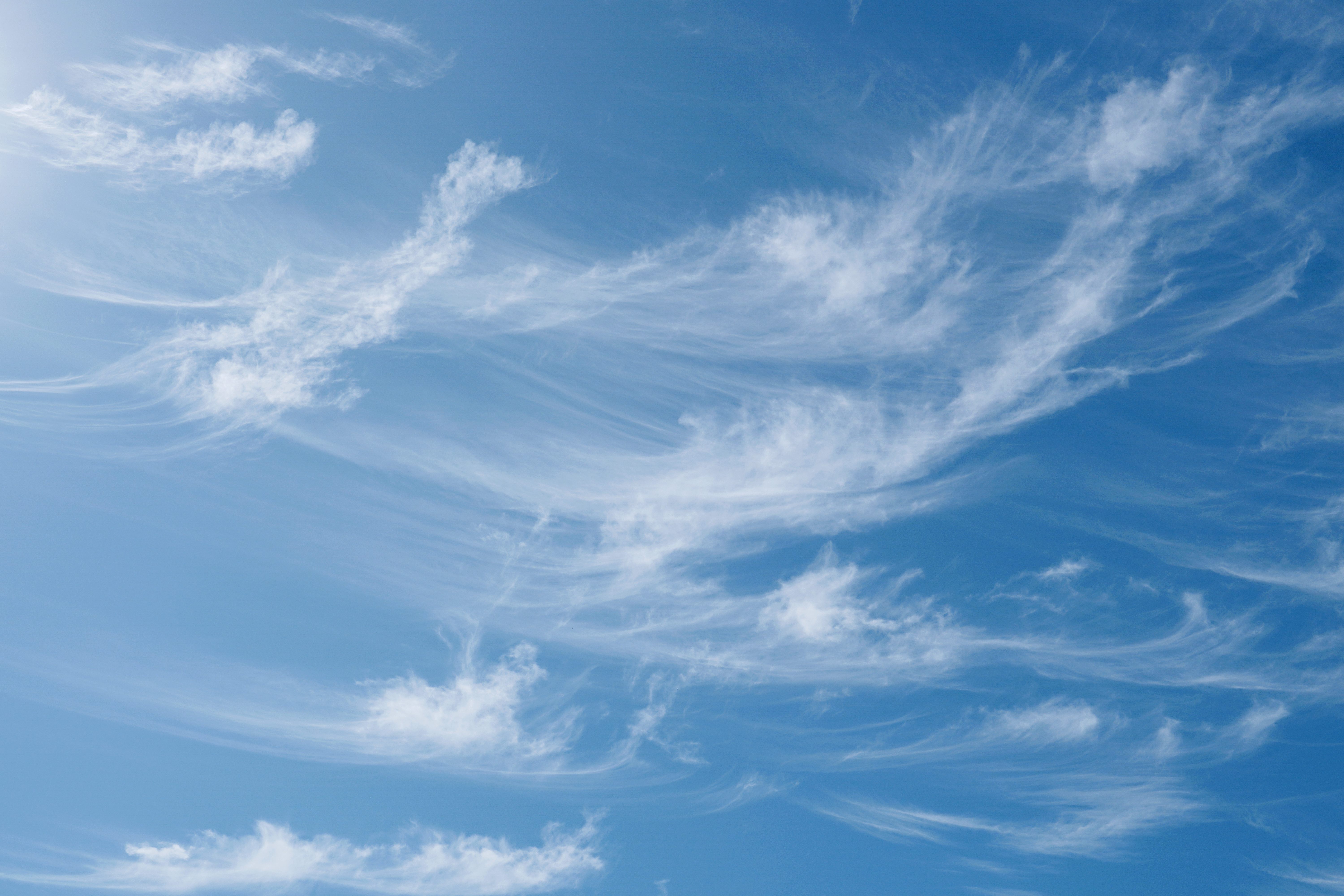Wispy white clouds drift across a bright blue sky.