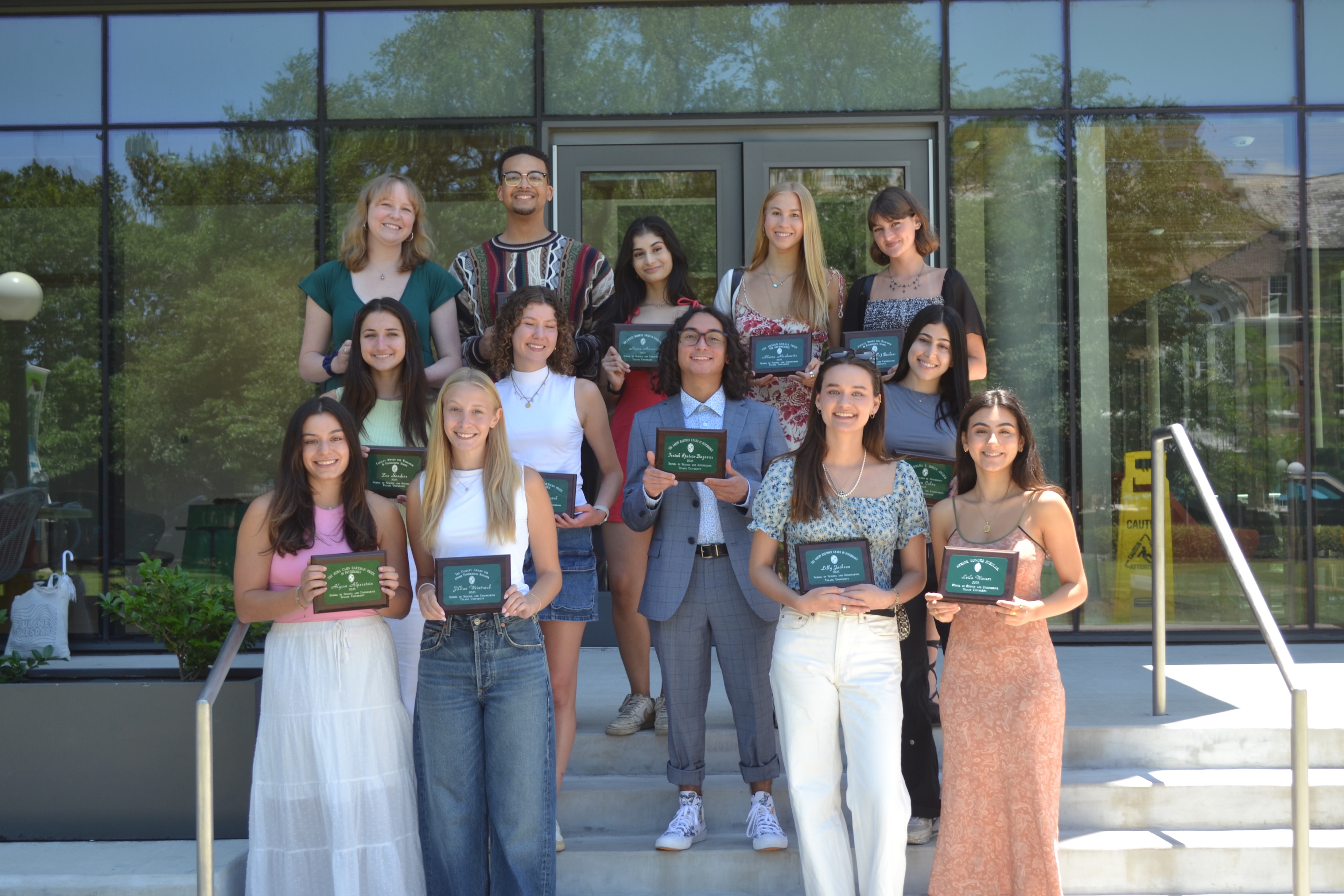 Group of students receiving awards outside a building.