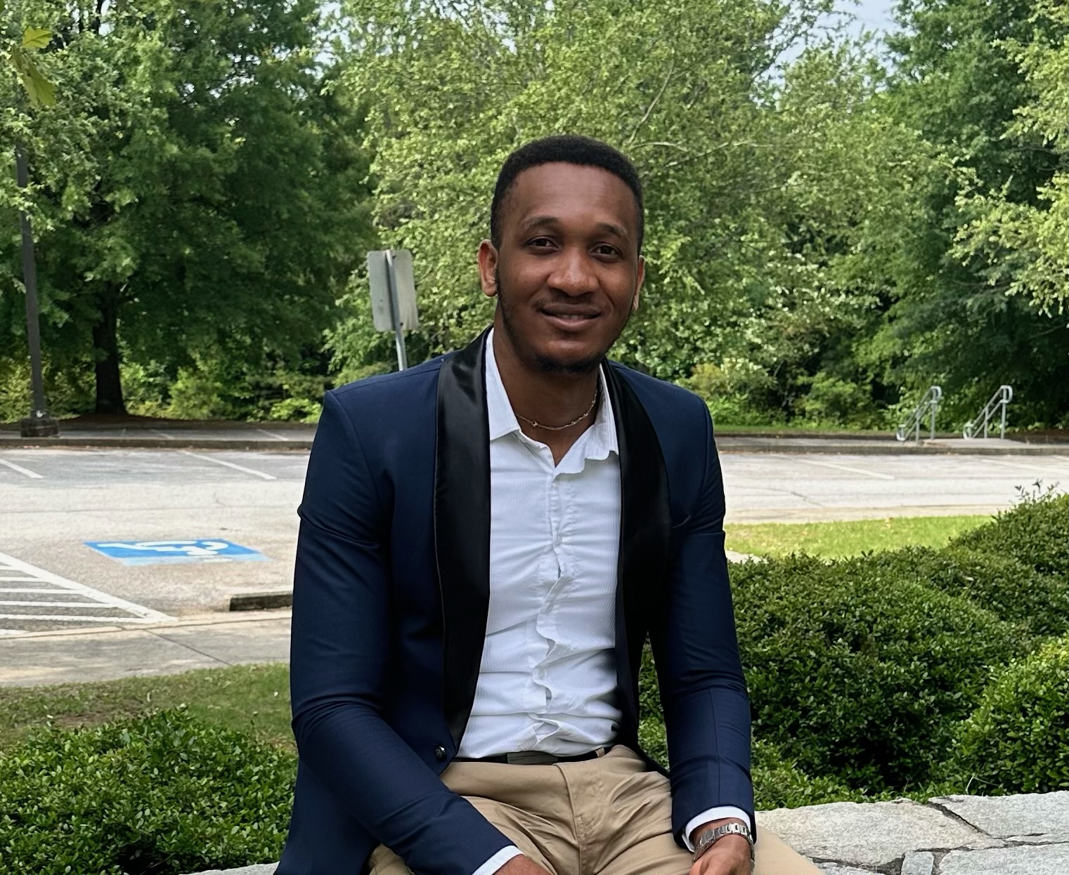 Man in blue tuxedo and white shirt smiles outdoors.
