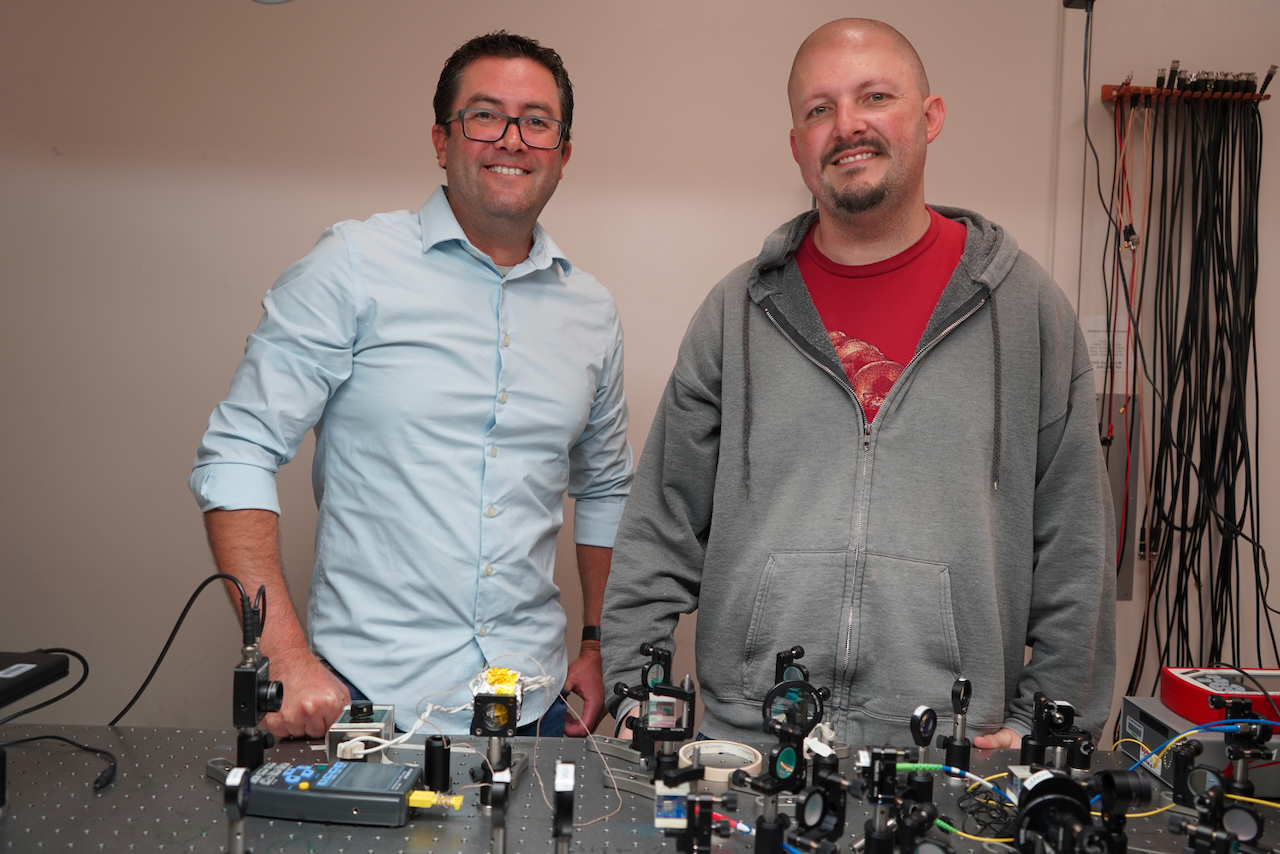 Two men standing behind a table with scientific equipment.