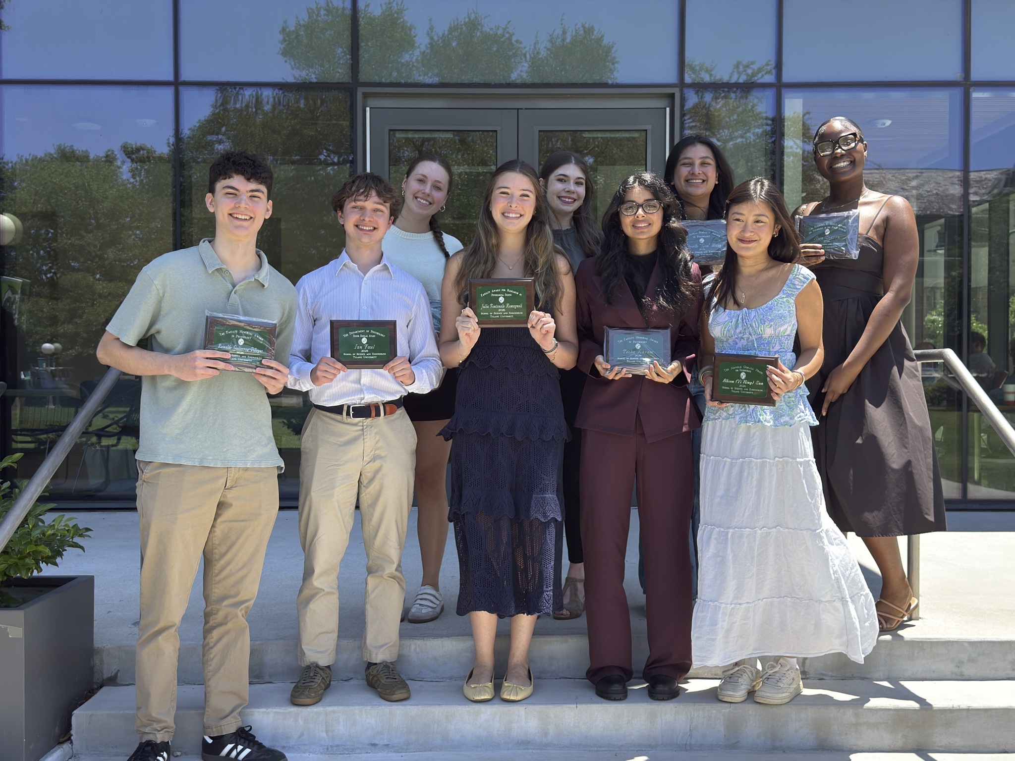 Group of students standing on stairs outside Paul Hall with awards