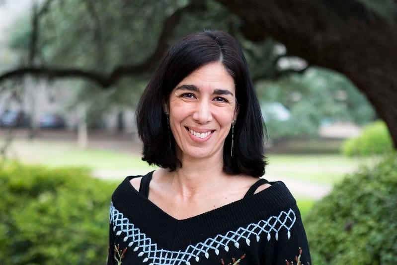 Smiling woman with dark hair and a patterned top, outdoors.