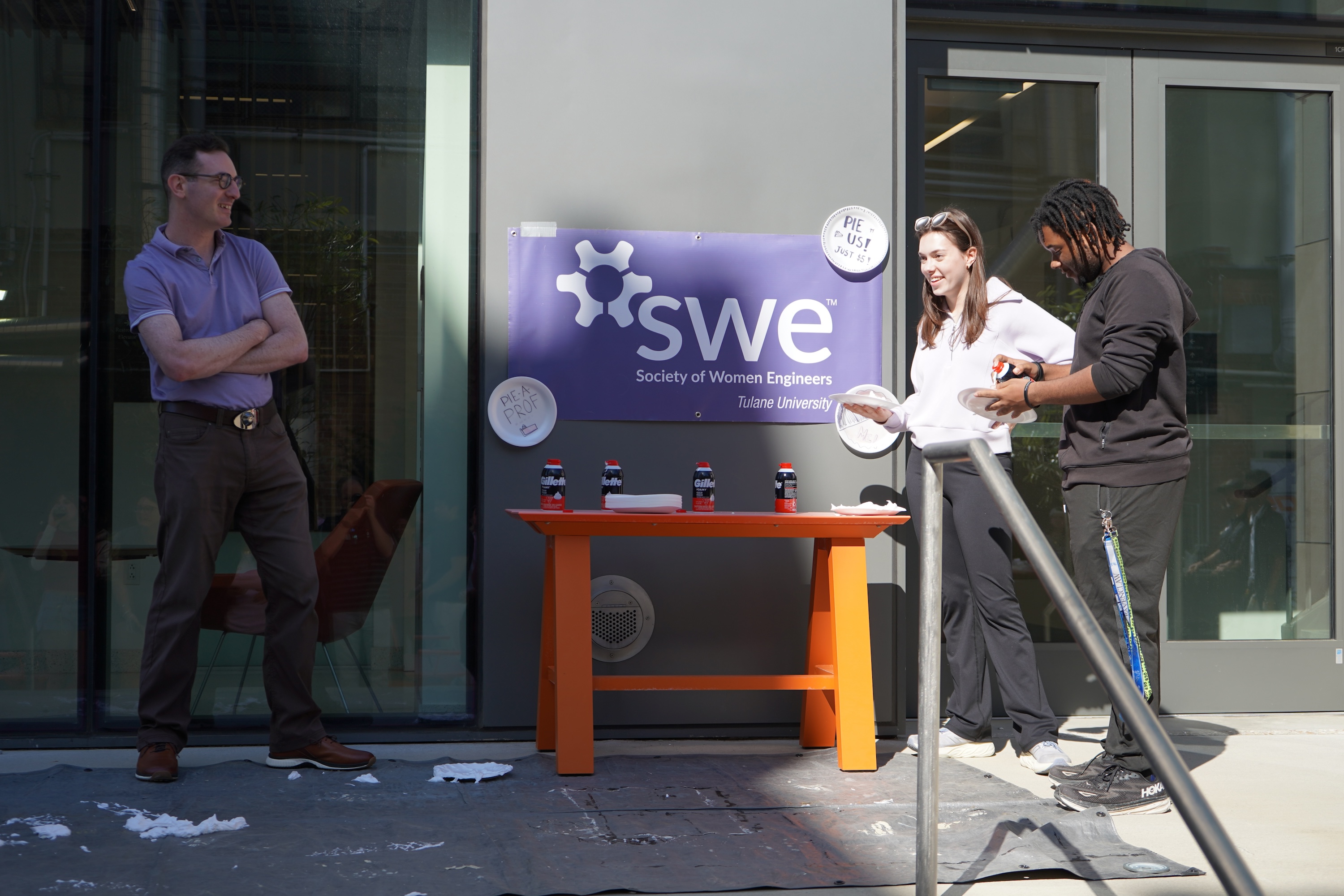 Three people by a table with "SWE" logo.