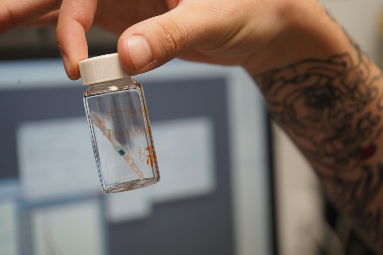 Man's hand holding a small glass jar
