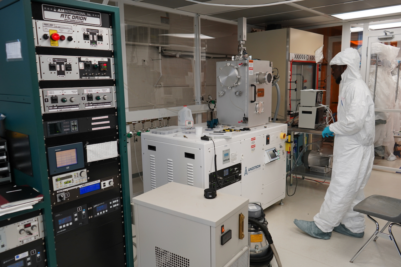Photograph of a researcher in a cleanroom working with scientific equipment.