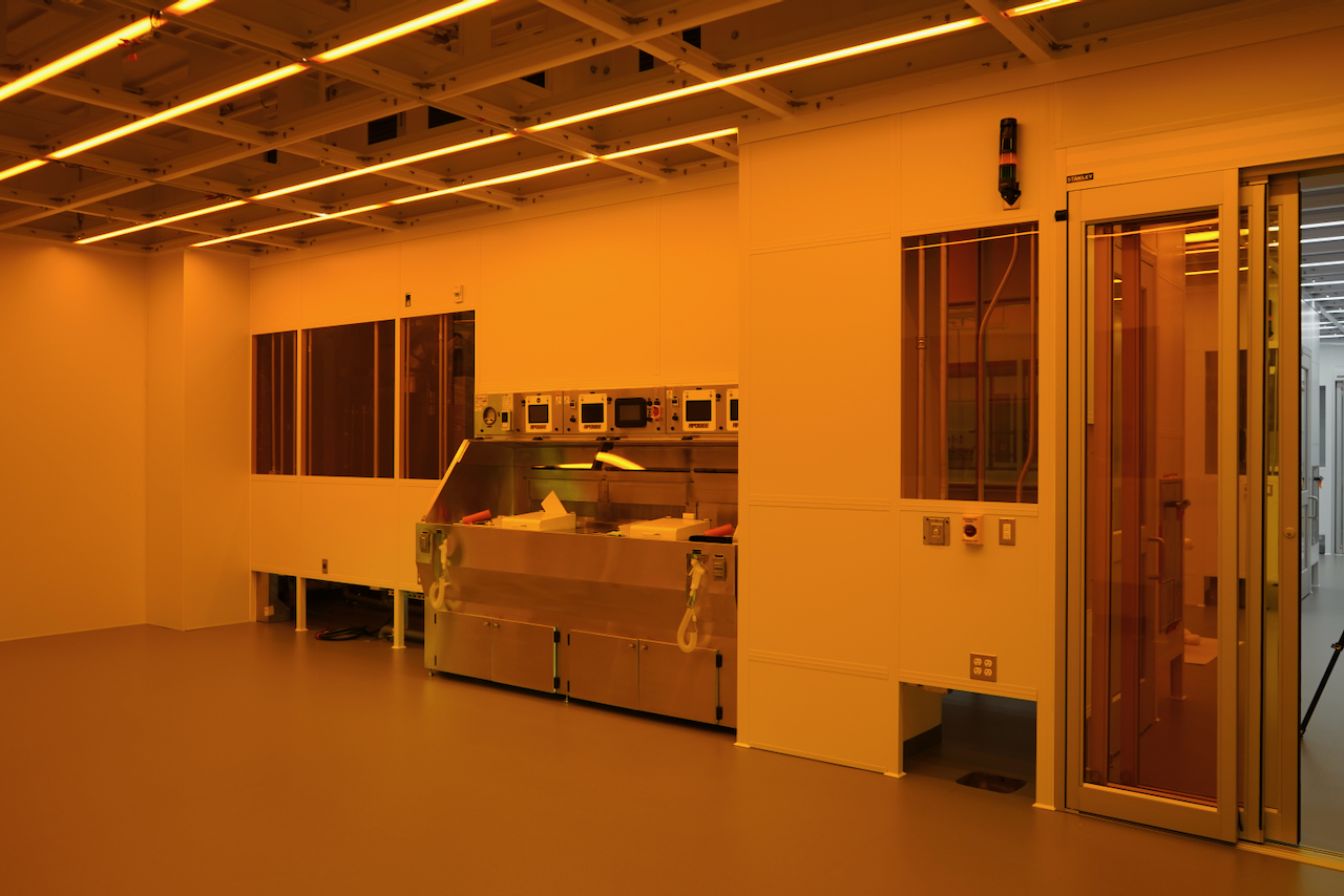 Clean room with yellow lighting and specialized equipment.