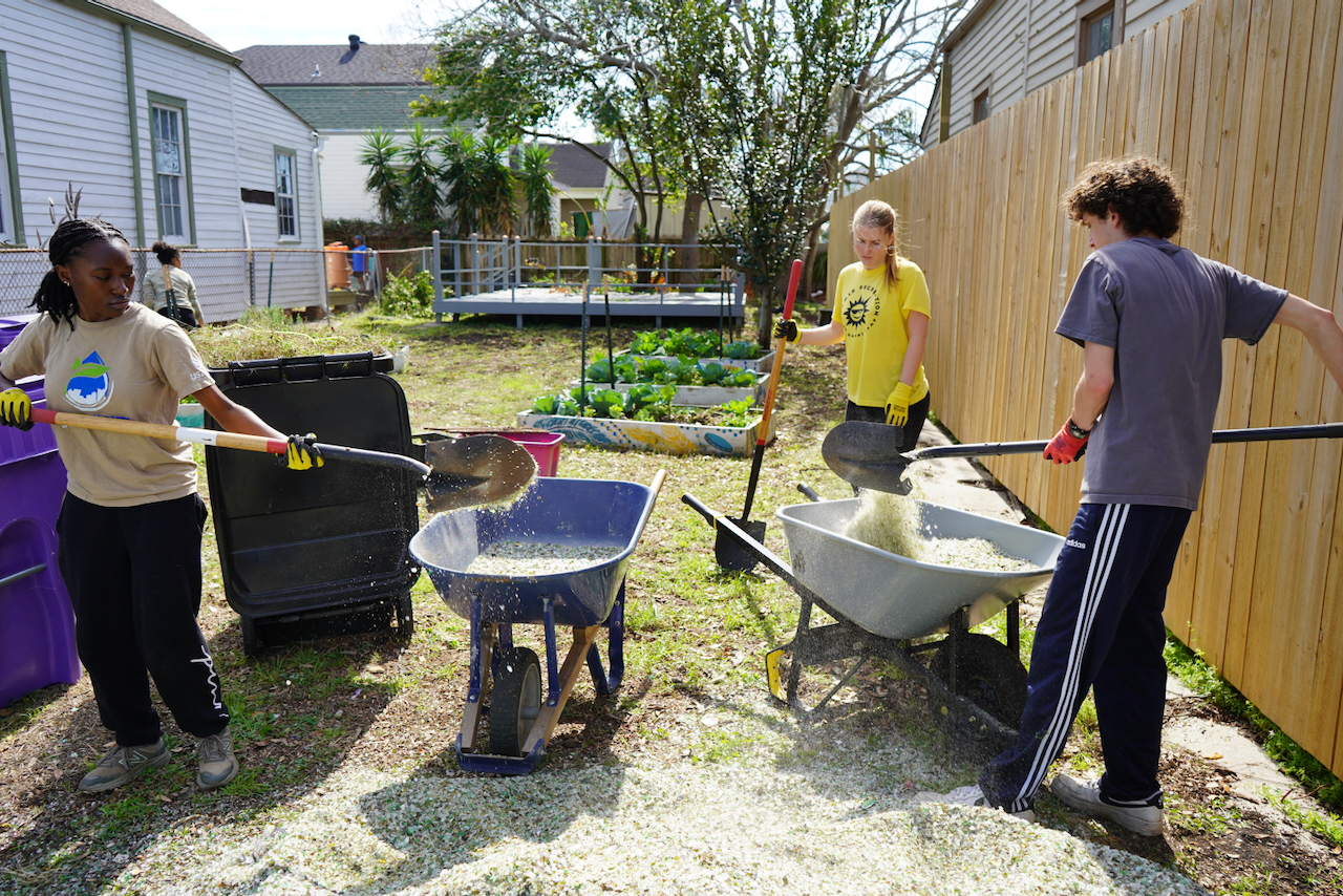 three students outside gardening with shovels