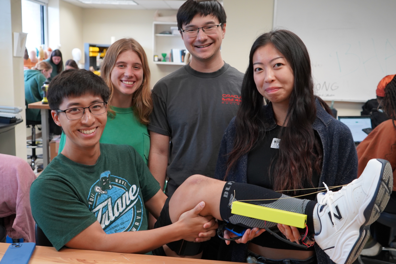 four students smiling with foot device attached to a leg