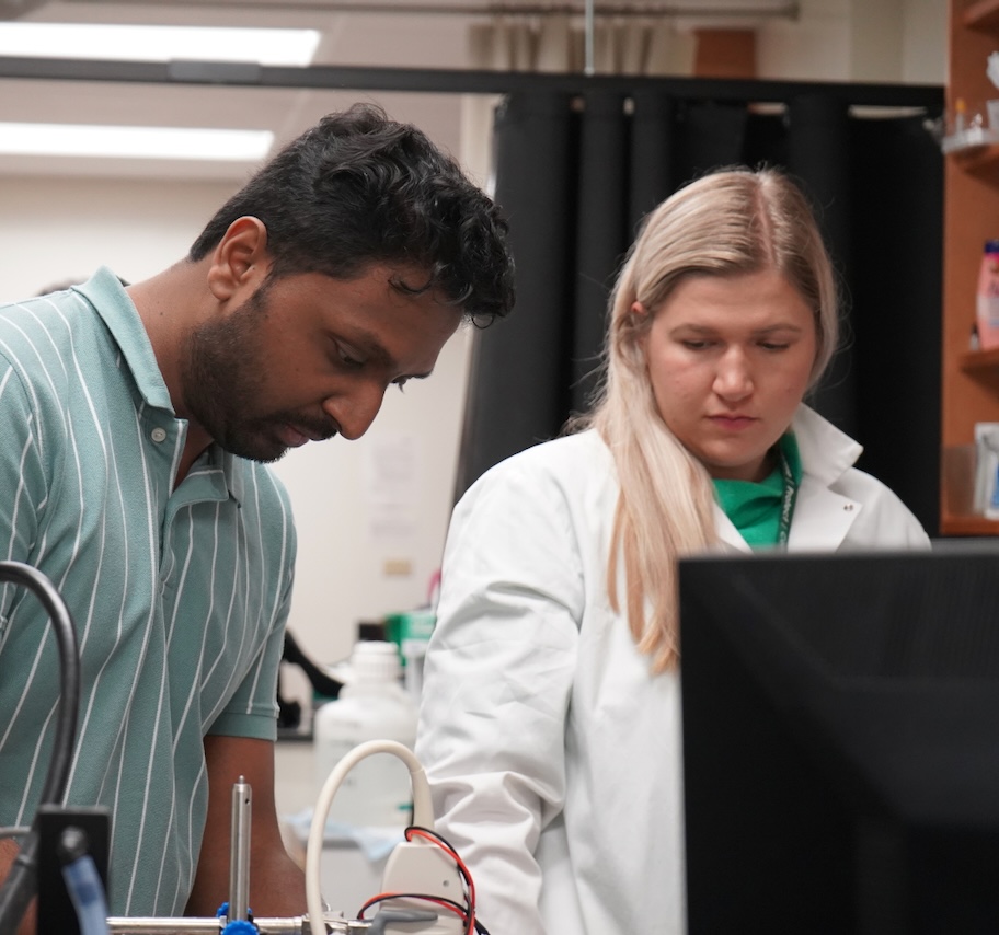 Photograph of a man and a woman in a lab, working together at a computer.