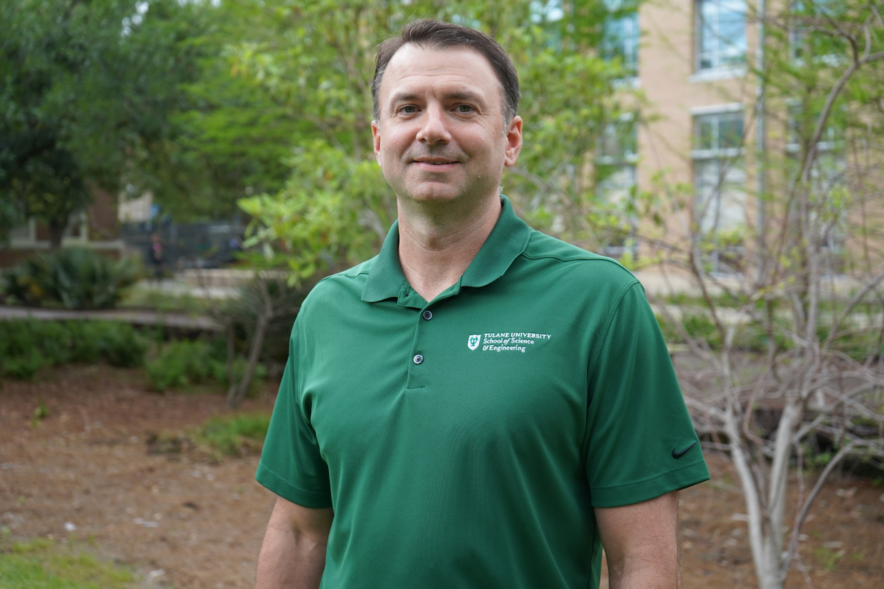 Photograph of a middle-aged man in a green polo shirt standing outside.