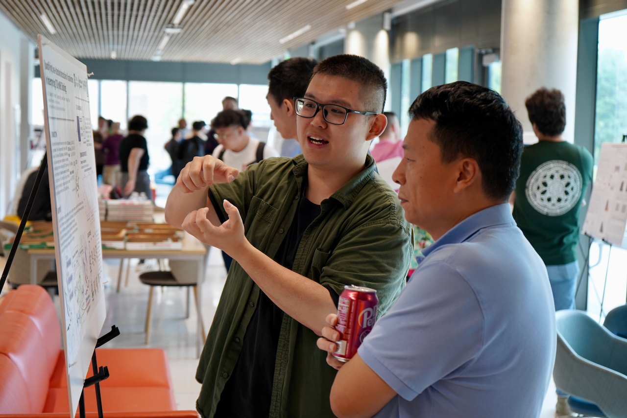 Photograph of two young men discussing a poster in a modern room.