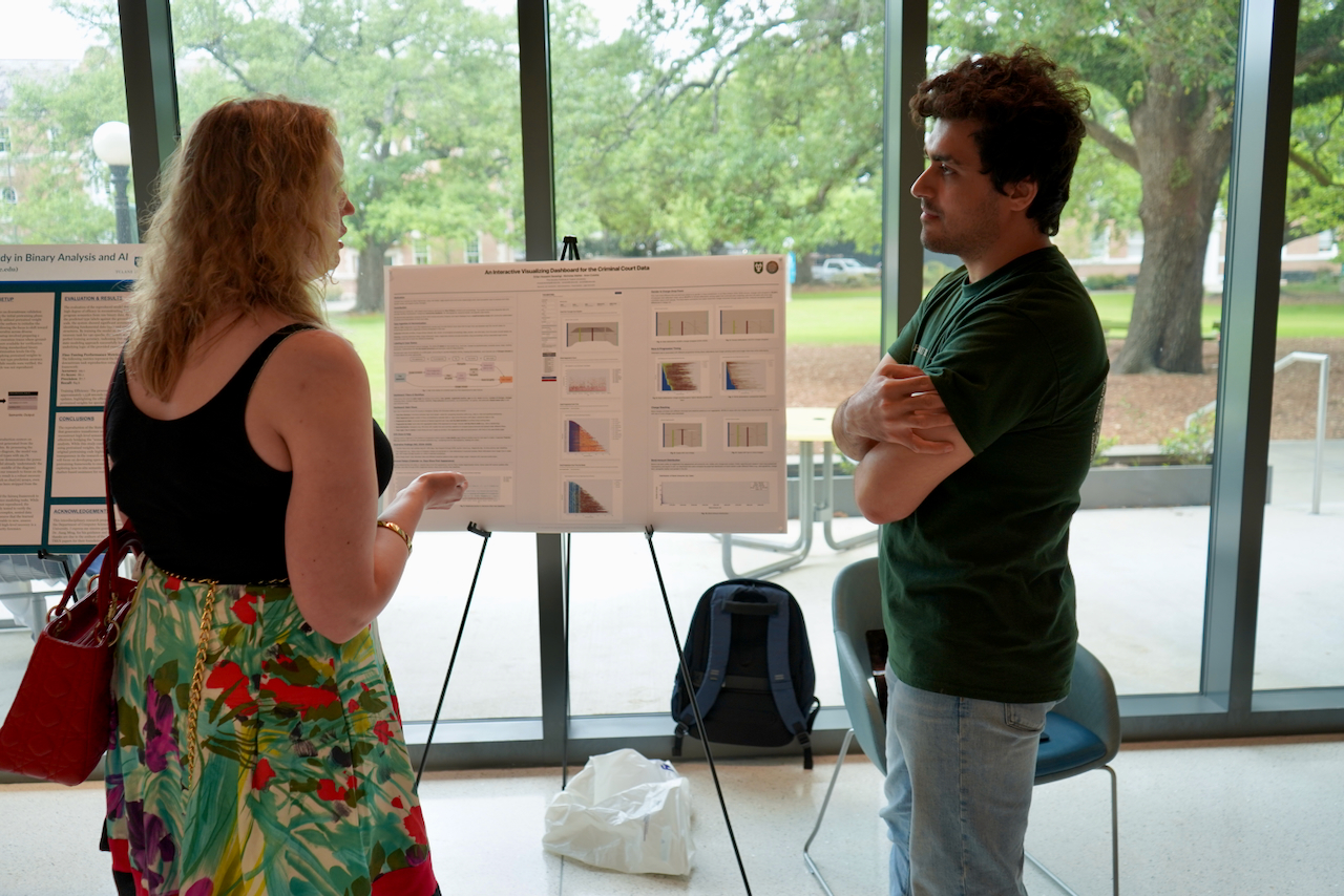 Photograph of a woman presenting a poster to a man in an indoor setting.