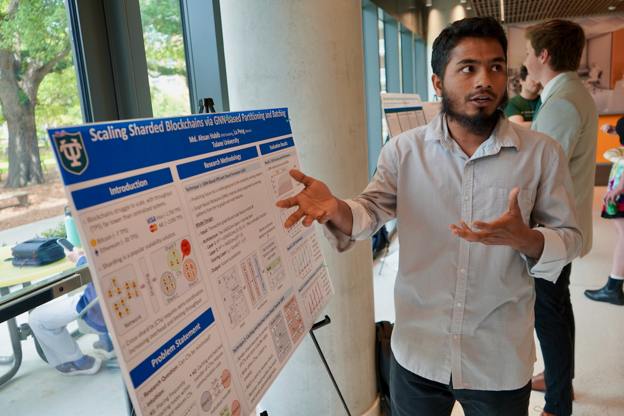 Man presenting a research poster with diagrams and text, gesturing with his hands.