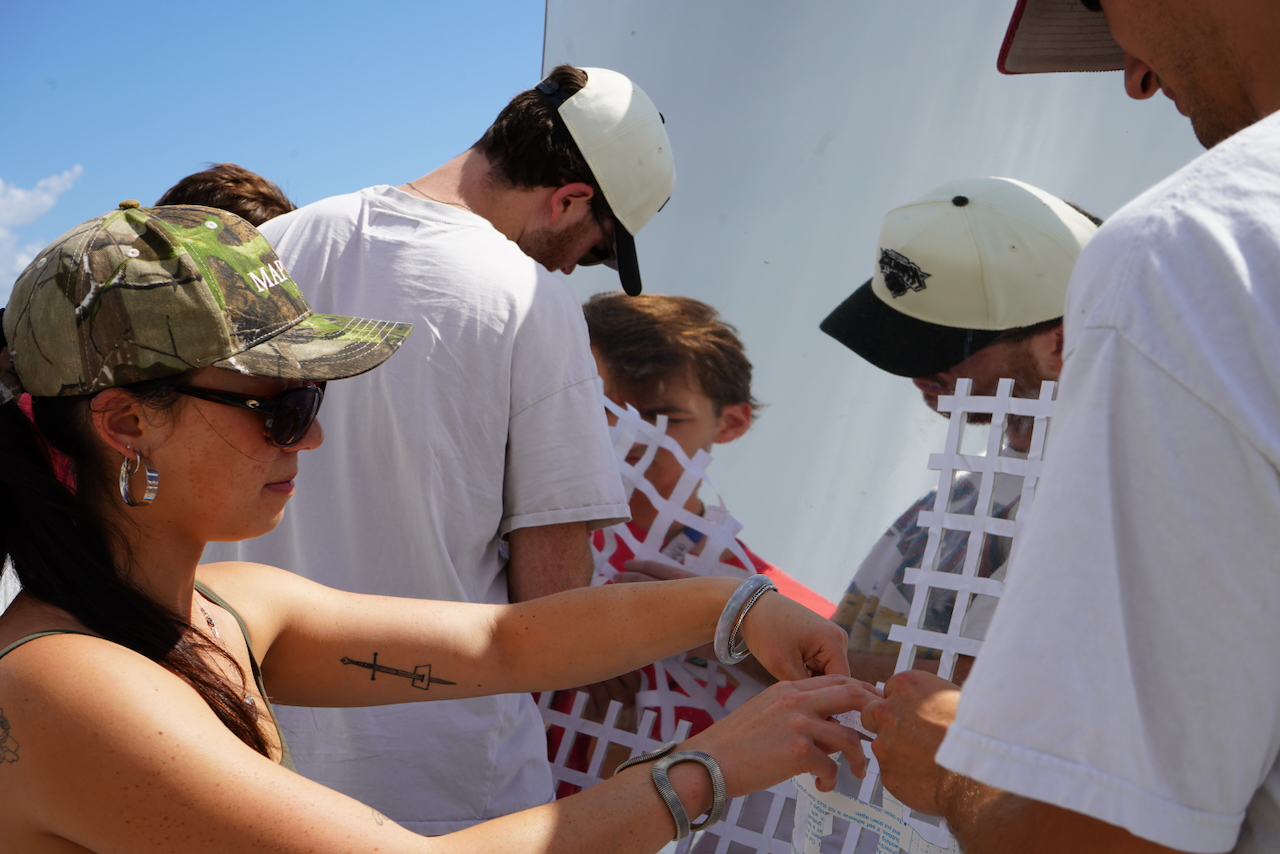 Photograph of people assembling white plastic lattice outdoors.