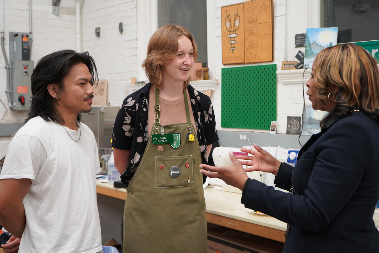 Photograph of three people talking in an art studio.