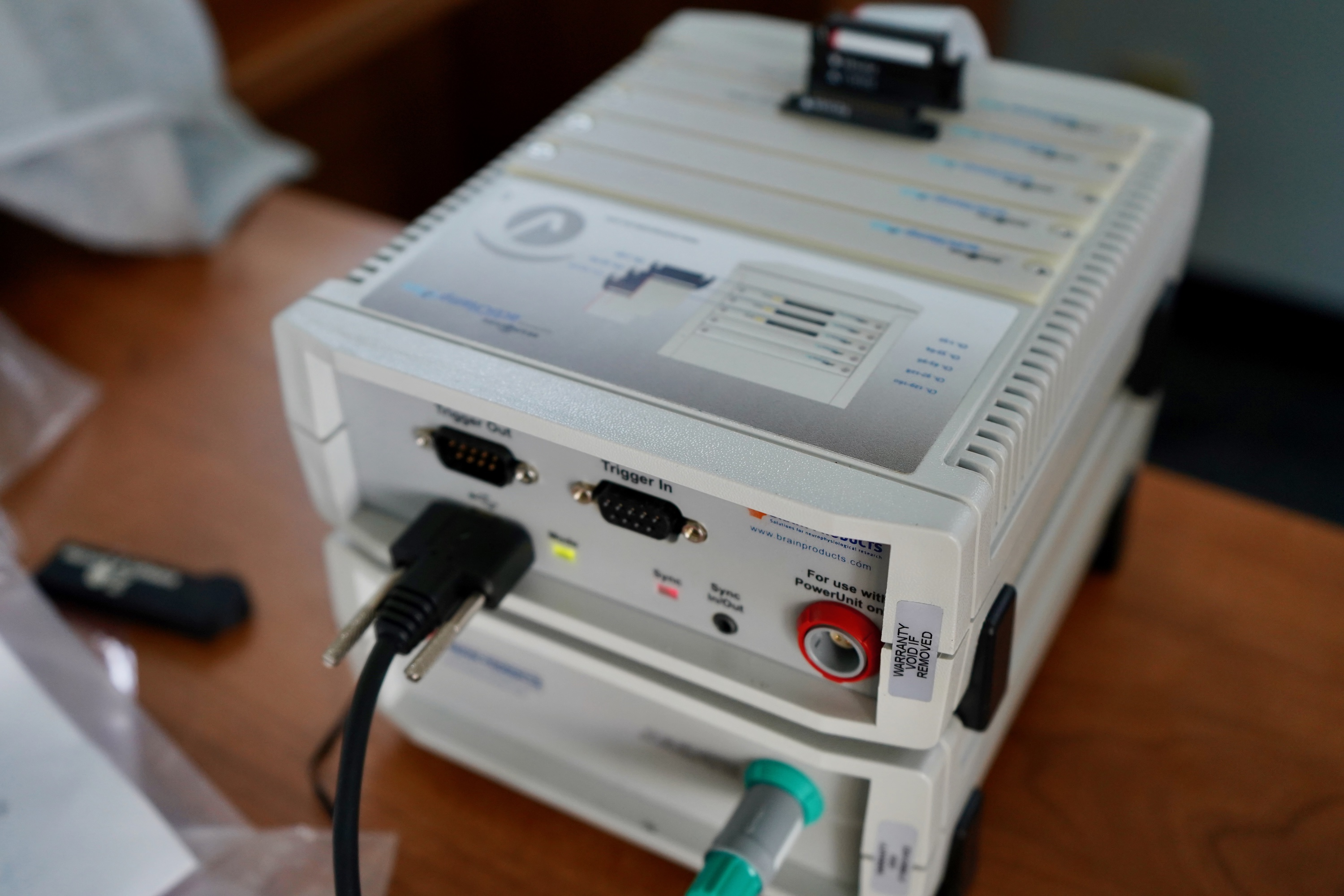 Photograph of a modular scientific instrument with ports and cables on a wooden table.