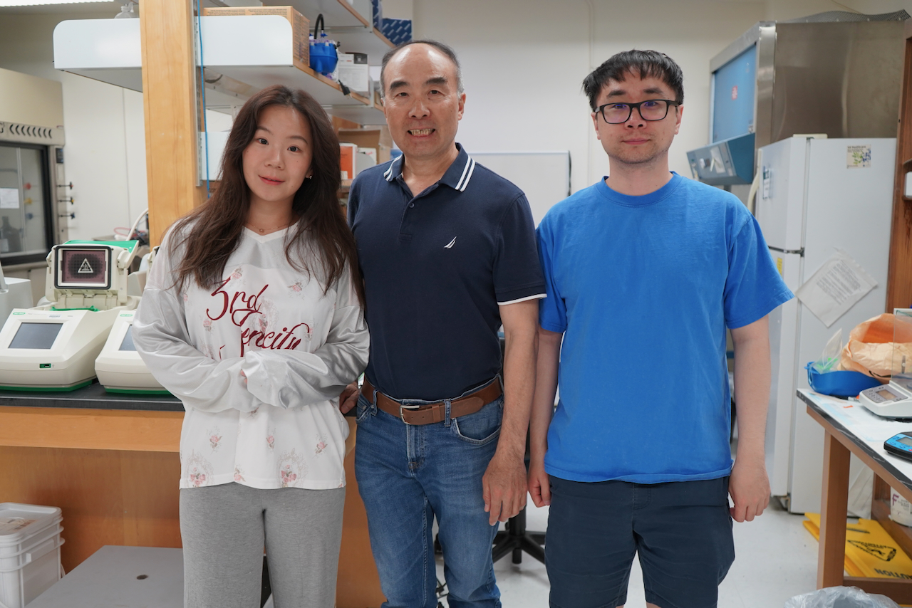 Photograph of a woman and two men standing together in a laboratory.