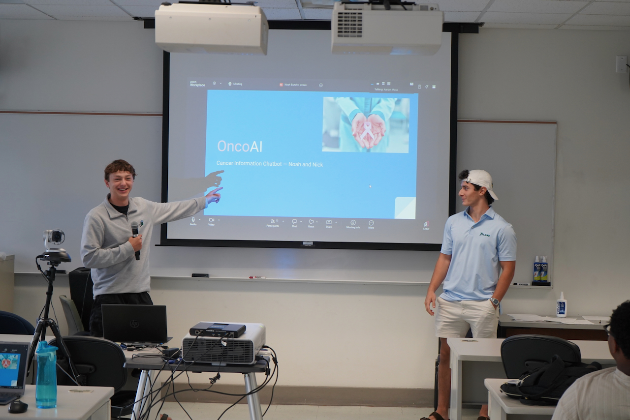 Photograph of two young men presenting in a classroom with a projector screen.