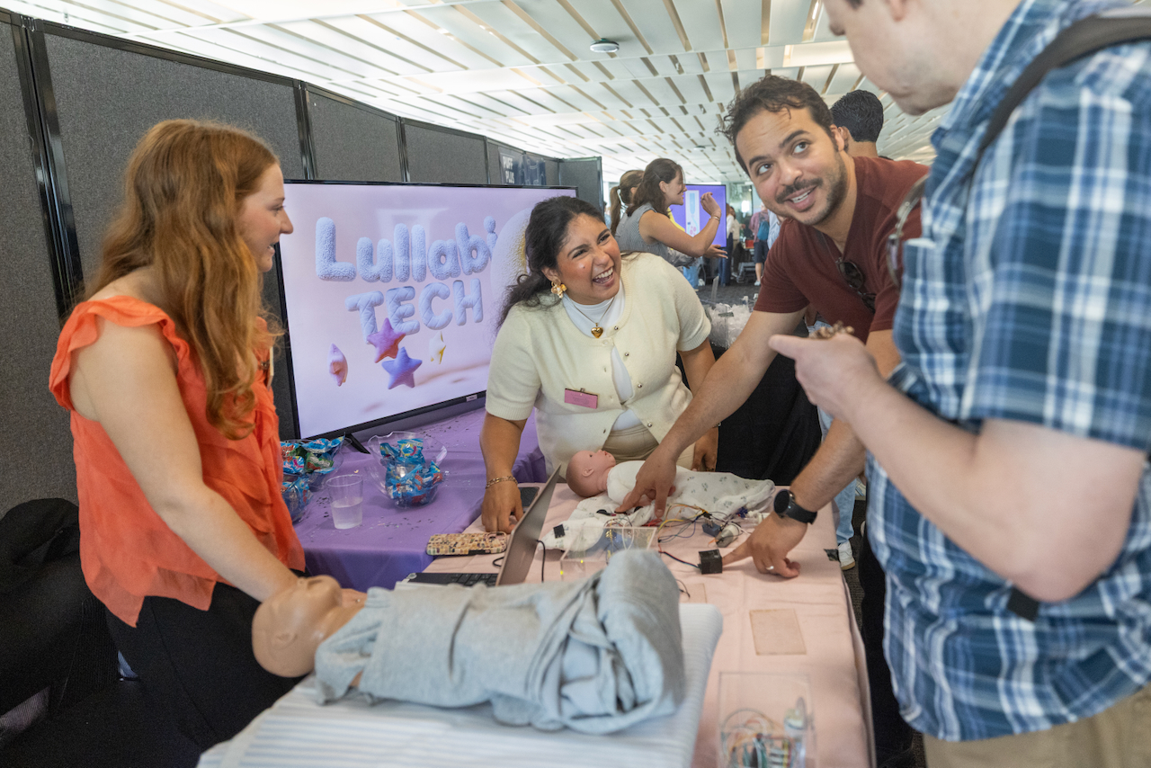 People interact at a Lullab Tech exhibit with a baby doll.