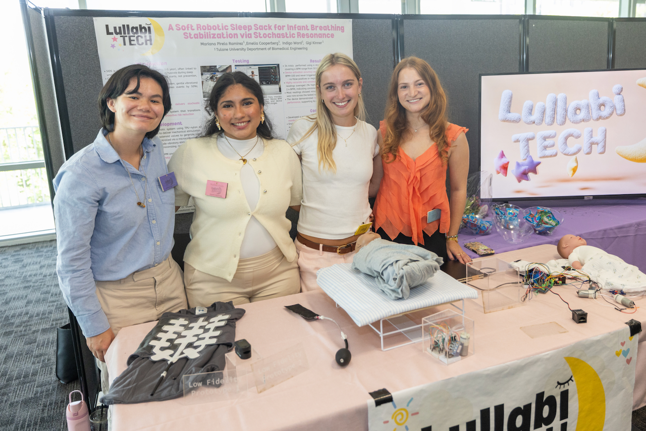 four students smiling with infant doll on table wearing medical device