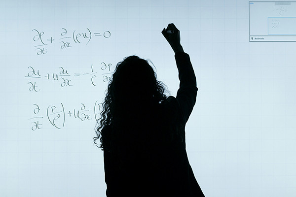 Silhouette of a woman drawing on a white board