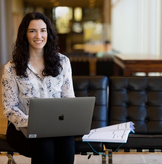 Woman with black hair sitting on a couch with a computer in her lap