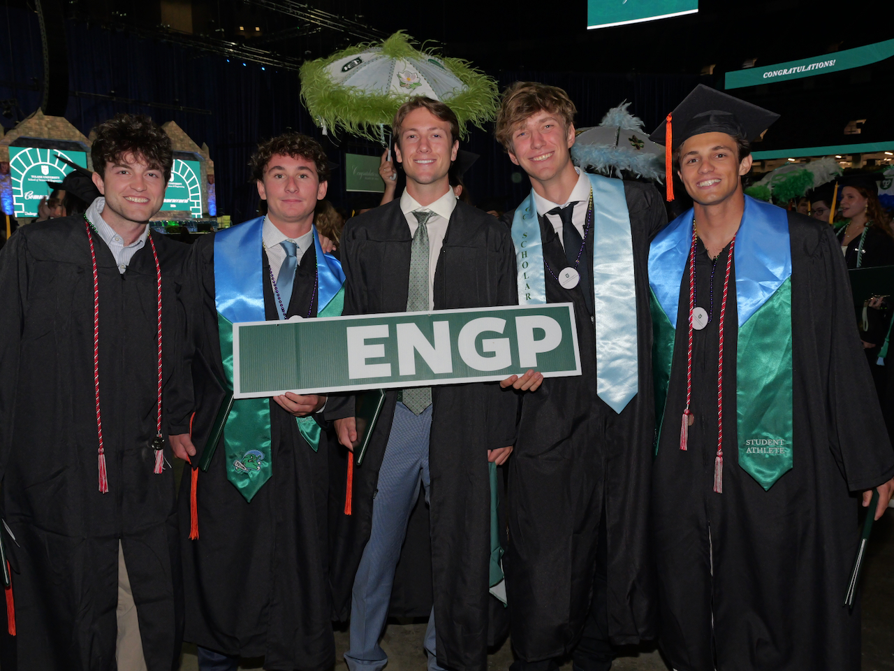 Five students in graduation regalia holding up a sign that says "ENGP"