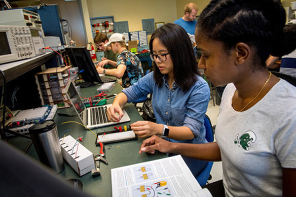 Students working on an electronics project at a workbench.