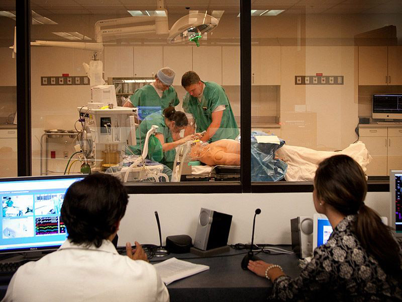 Medical students practice surgery on a dummy in a simulation lab.