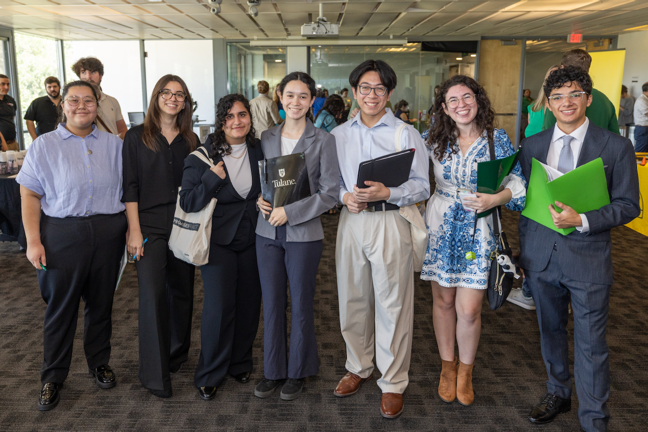 Group of young professionals stand together holding folders.