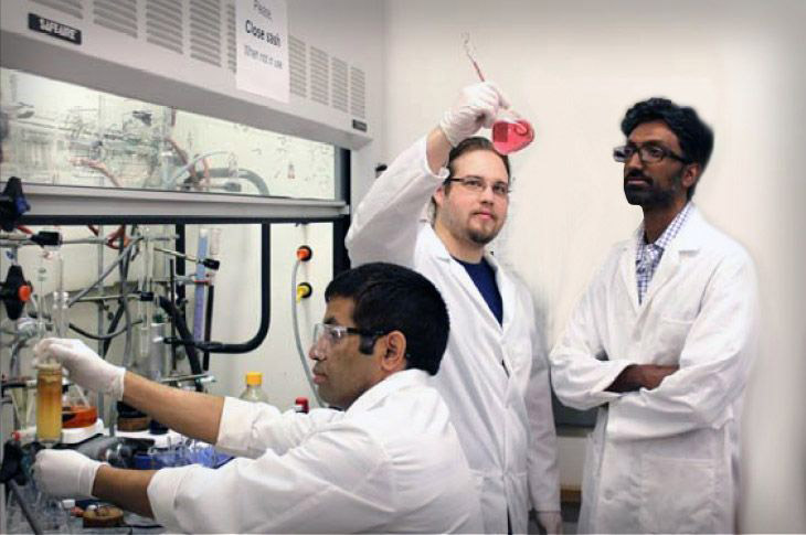 Three scientists in lab coats using lab equipment