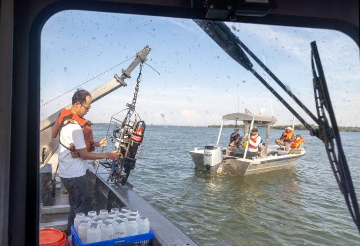 Photograph of researchers deploying equipment from a boat, with another boat nearby on the water.