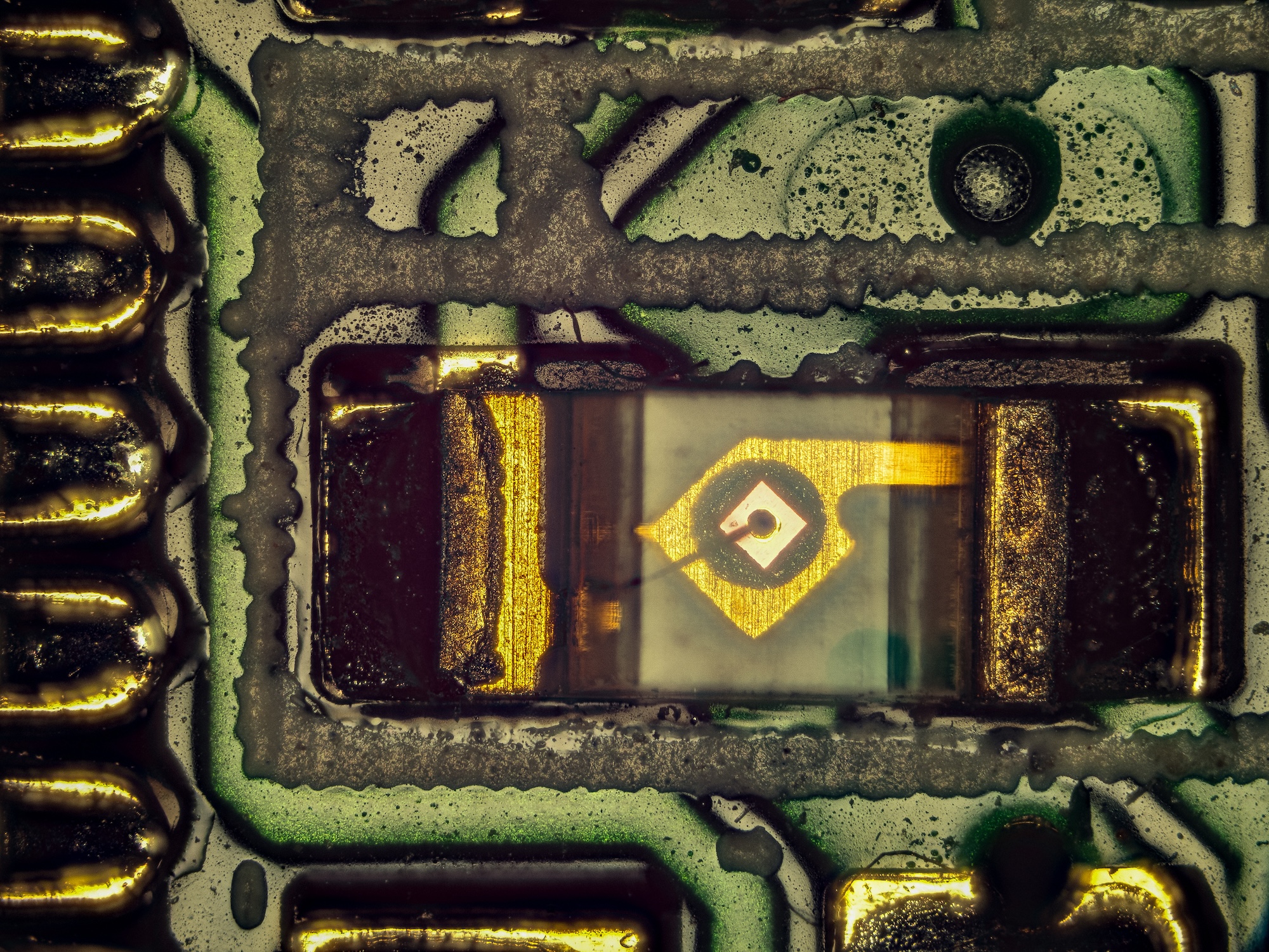 Macro photograph of a circuit board detail with a central square component.