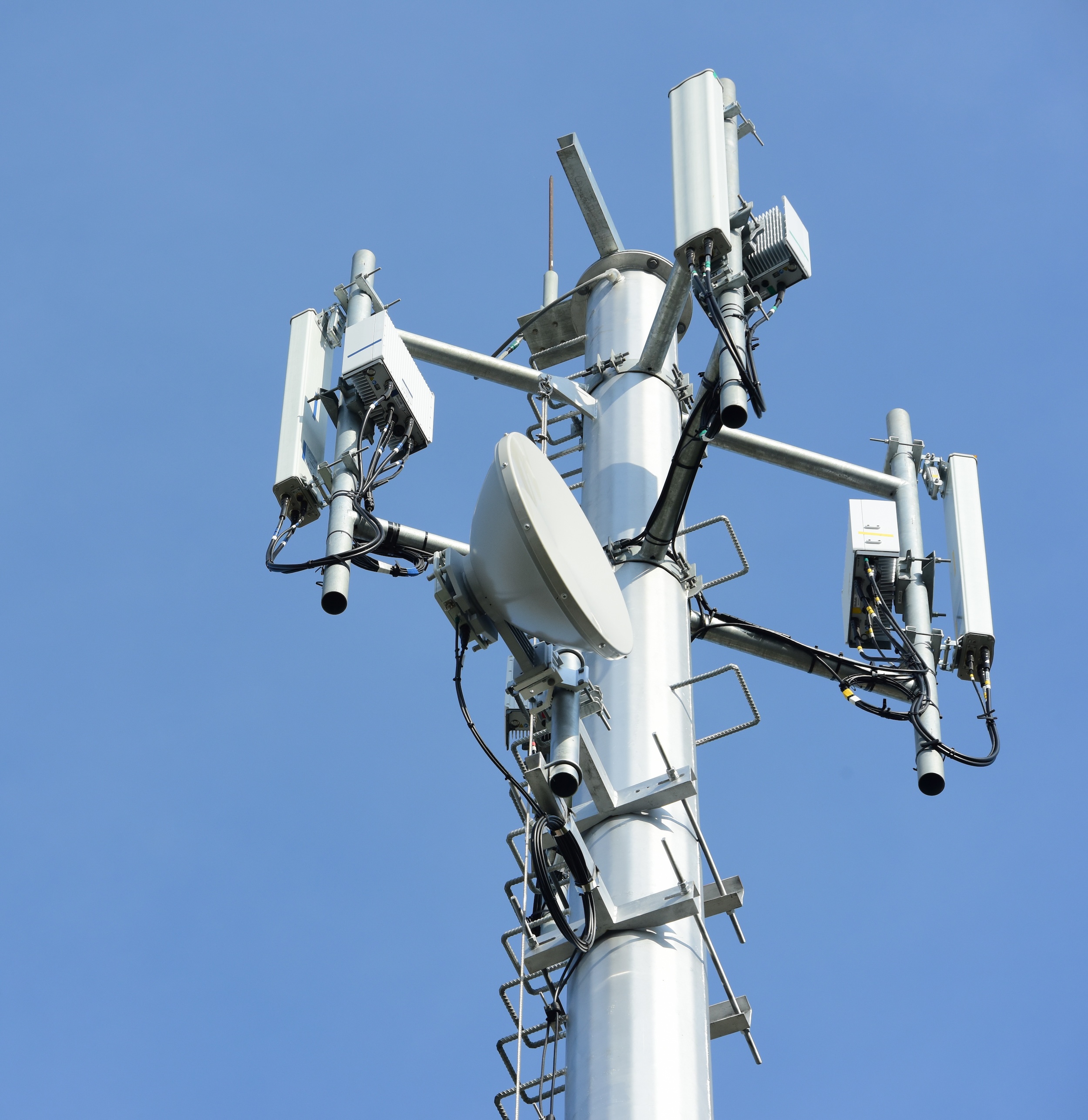 Photograph of a telecommunication tower against a clear blue sky.