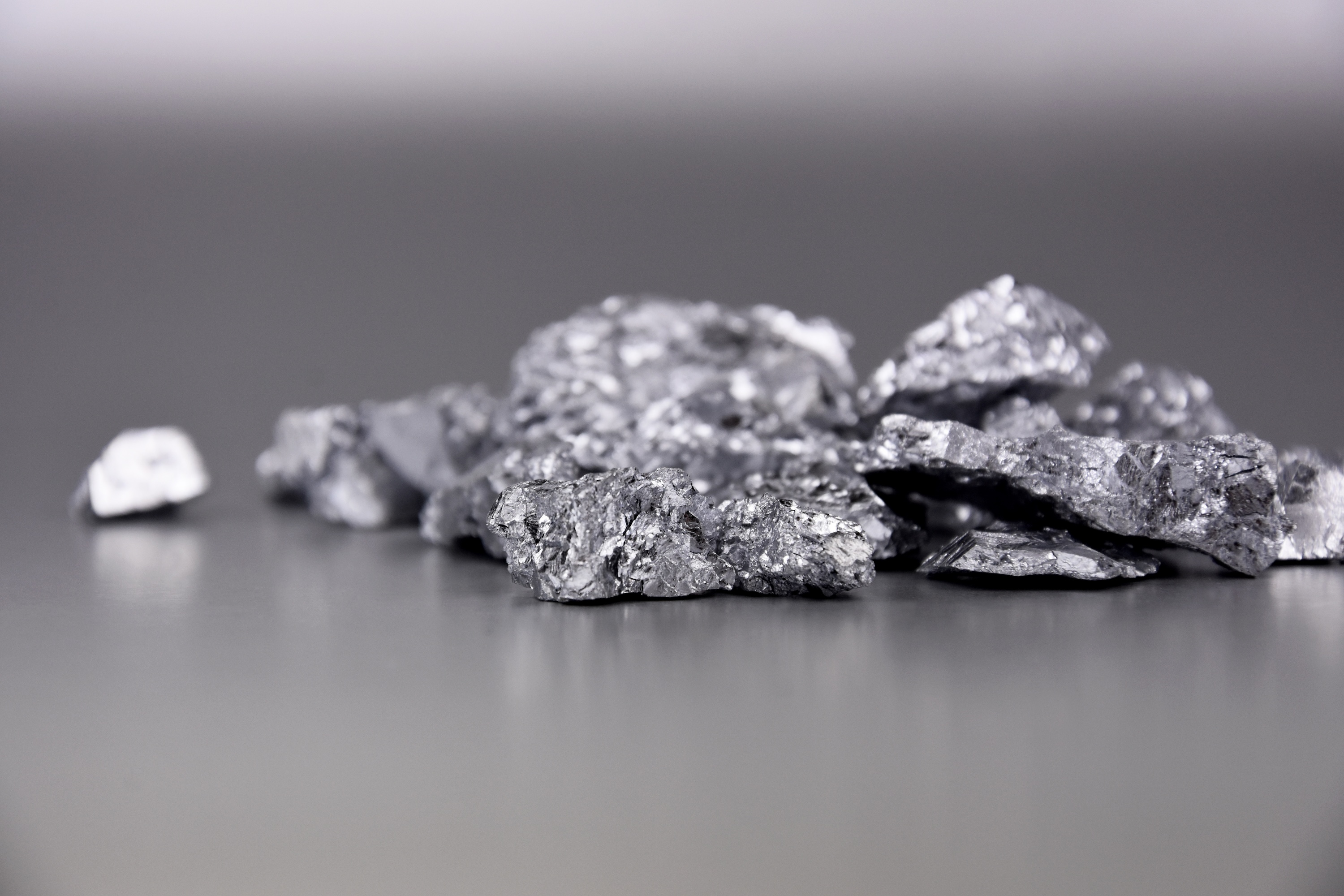 Close-up of chunks of silver metallic material on a grey surface