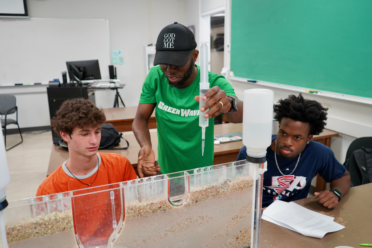 A photograph of a teacher and two students conducting a science experiment in a classroom.