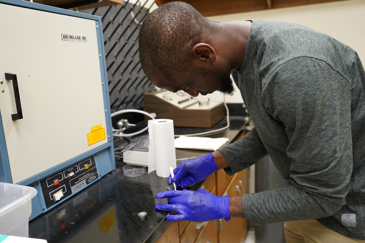 Photograph of a scientist wearing blue gloves working in a laboratory.