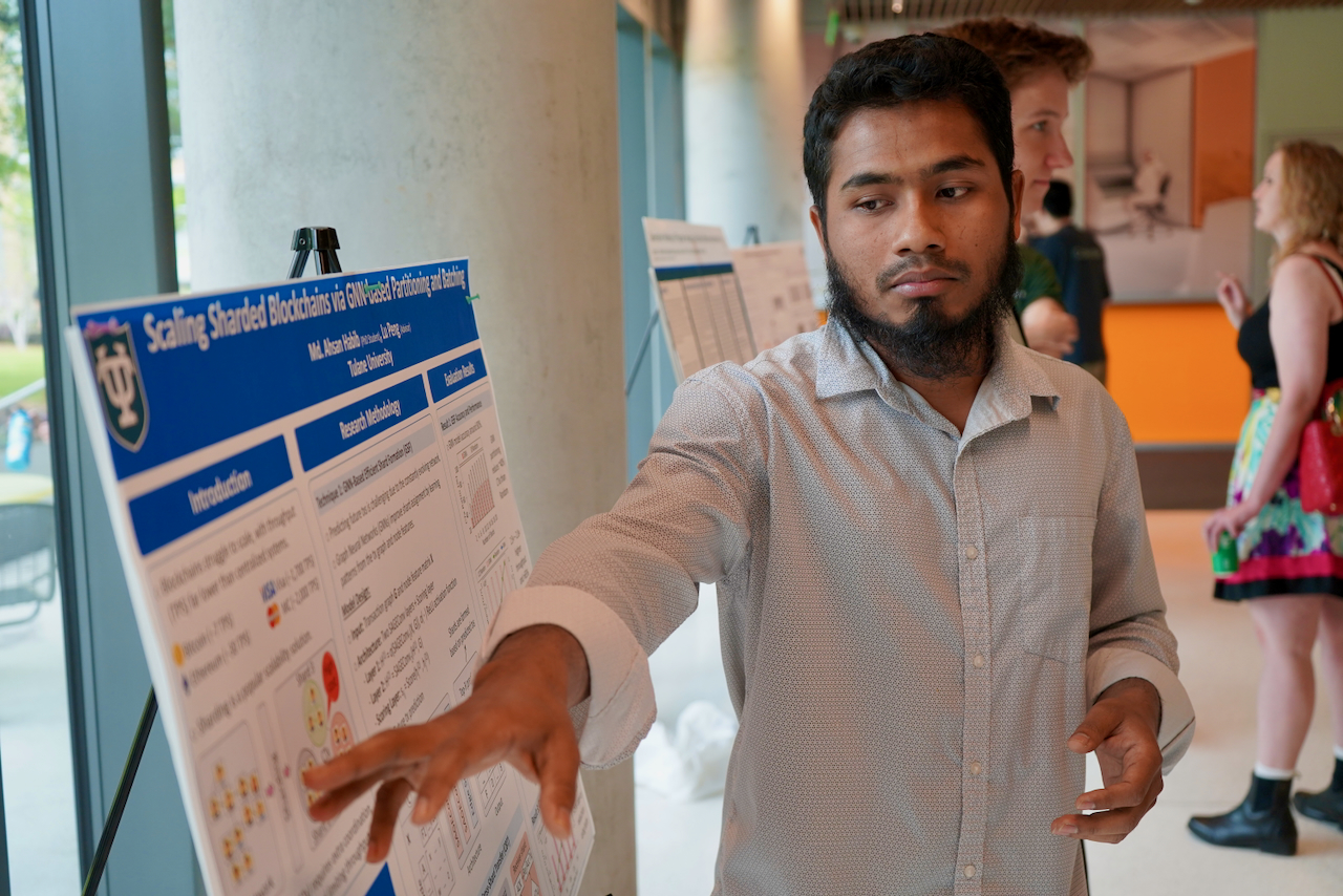 Man with beard pointing to a blue and white research poster