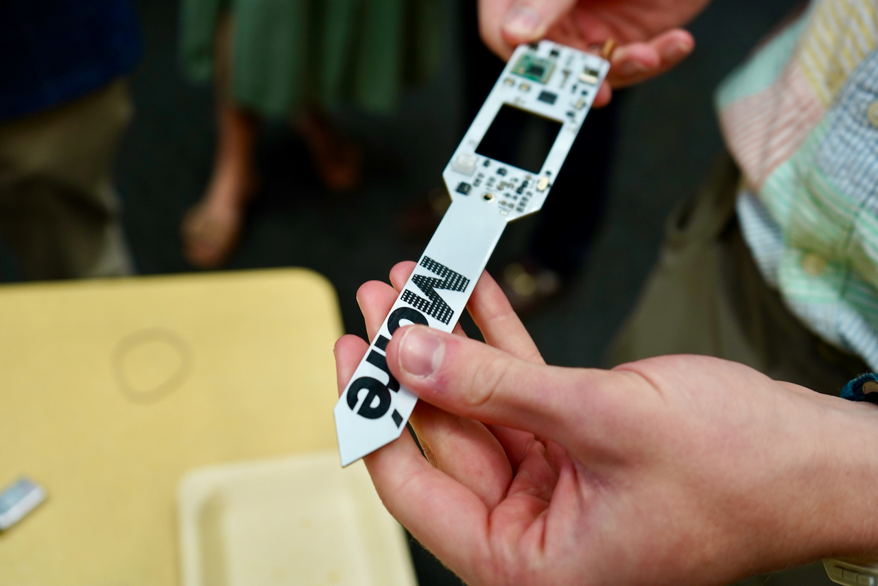 A person holds a narrow circuit board featuring the word "Modé".
